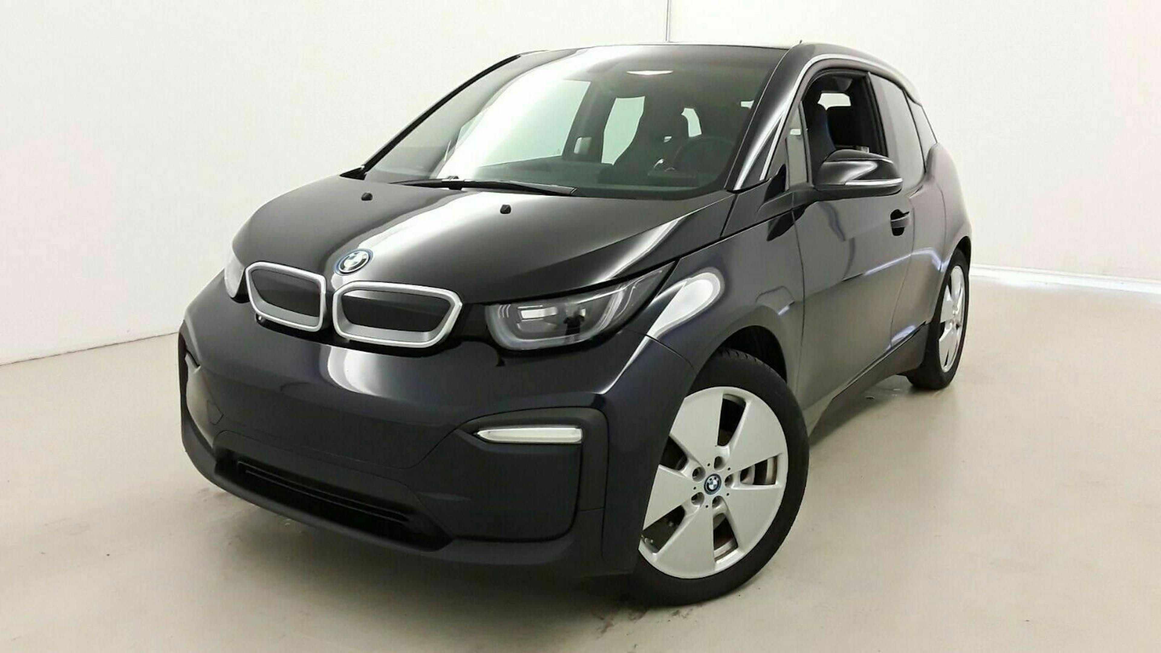 Ein schwarzer BMW i3 steht in einem Raum mit weißen Wänden und hellgrauem Boden.