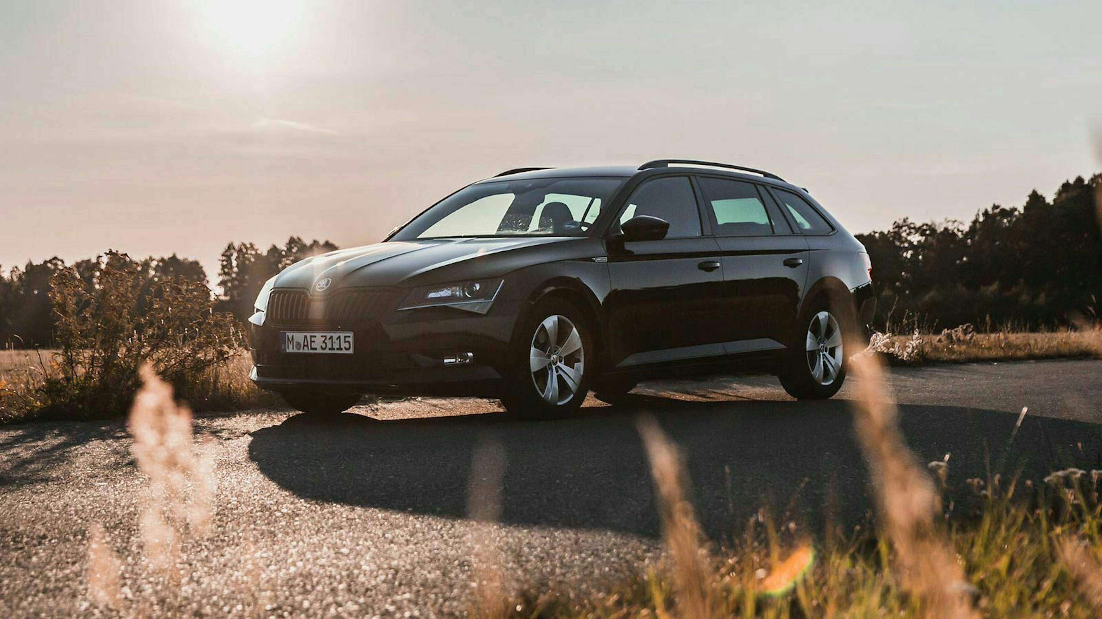 Ein schwarzer Skoda Superb von der Autovermietung Sixt steht im Sonnenlicht auf einer Landstraße