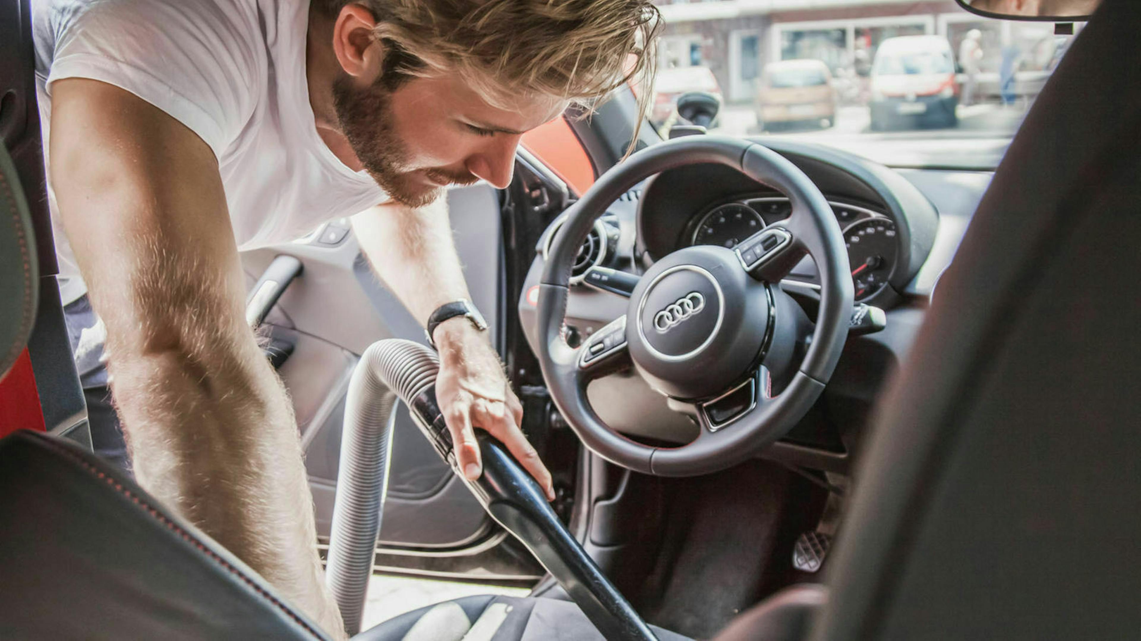 Ein Mann saugt den Innenraum seines Audi aus
