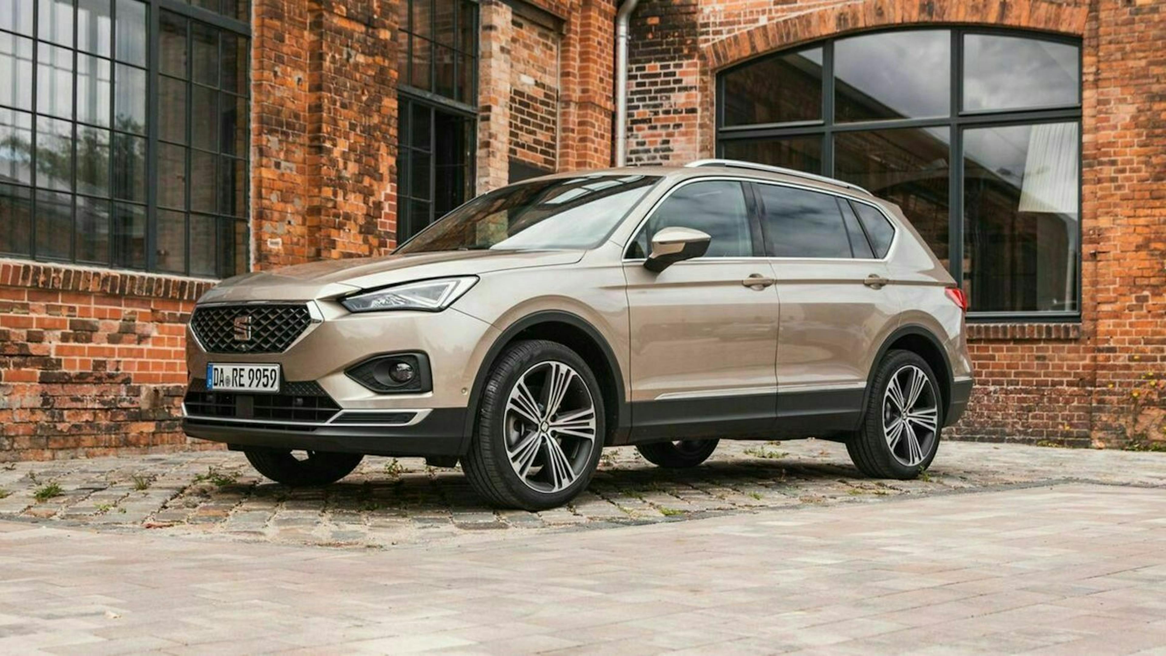 Ein brauner Seat Tarraco steht vor einem Gebäude mit Backsteinfassade