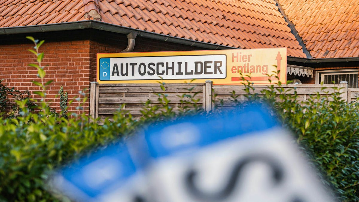 Ein Schild mit der Aufschrift "AUTOSCHILDER" weist den Weg zu einer Prägestelle in einem Kennzeichenshop