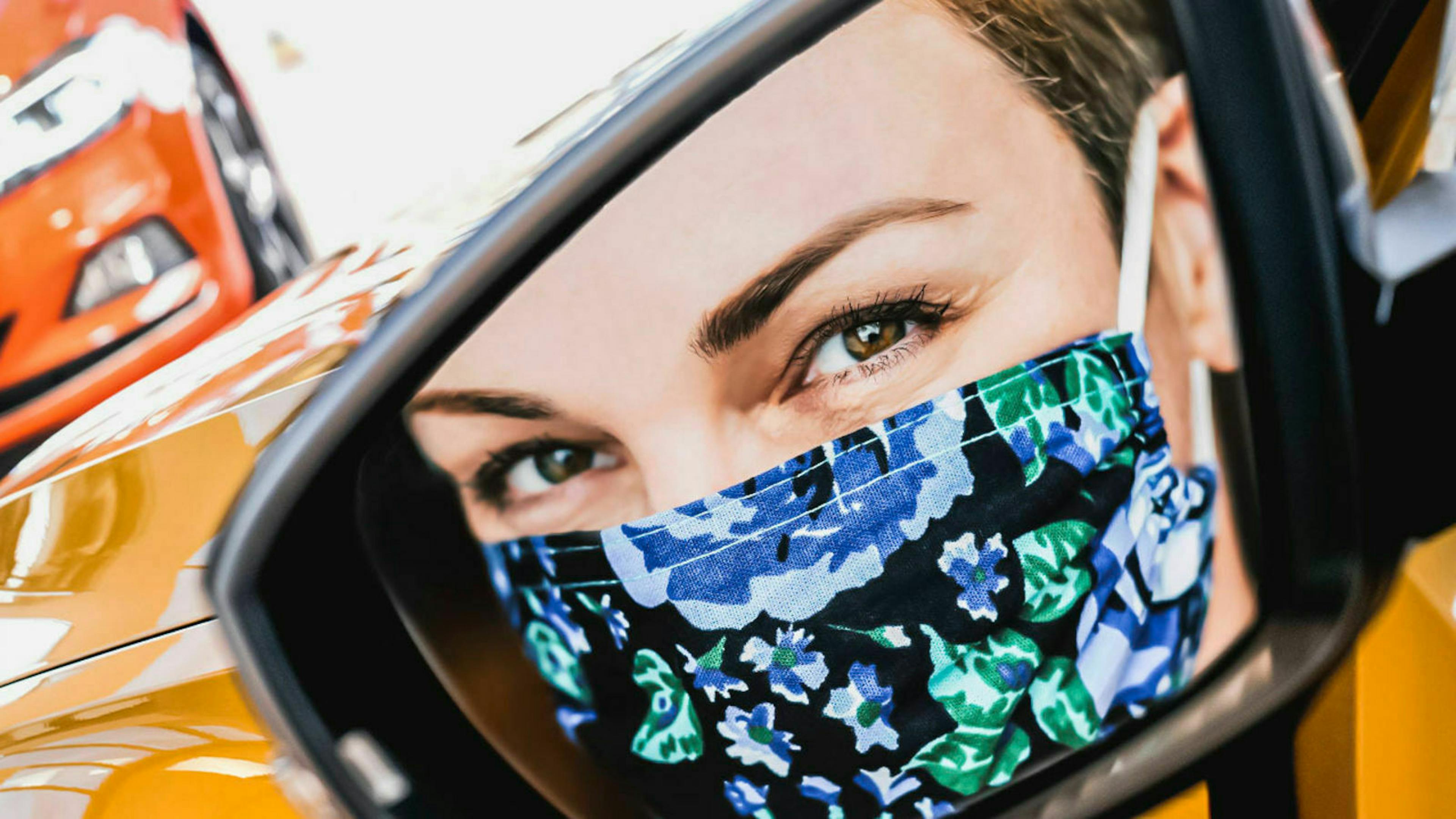 woman with mask in car mirror