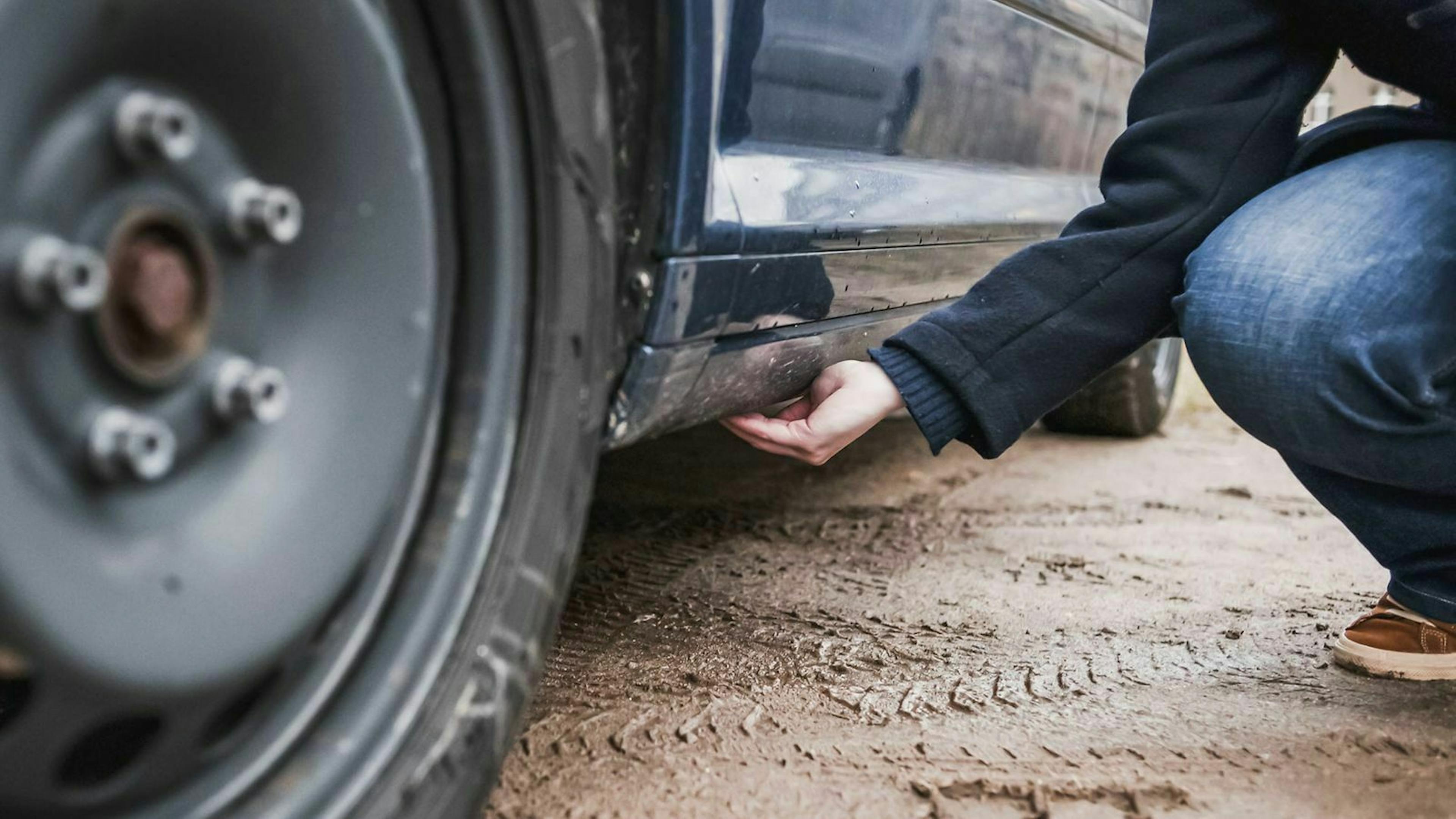 Jemand greift mit seiner Hand hinter den Seitenschweller um mögliche Roststellen zu finden. 