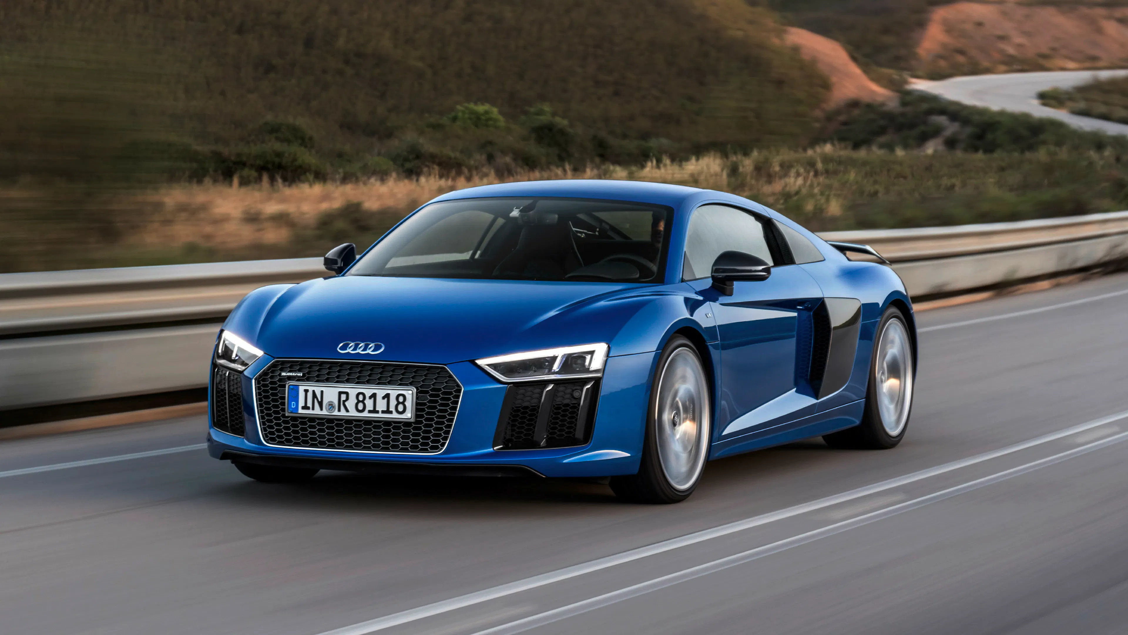 Ein blauer Audi R8 V10 fährt auf einer Landstraße.