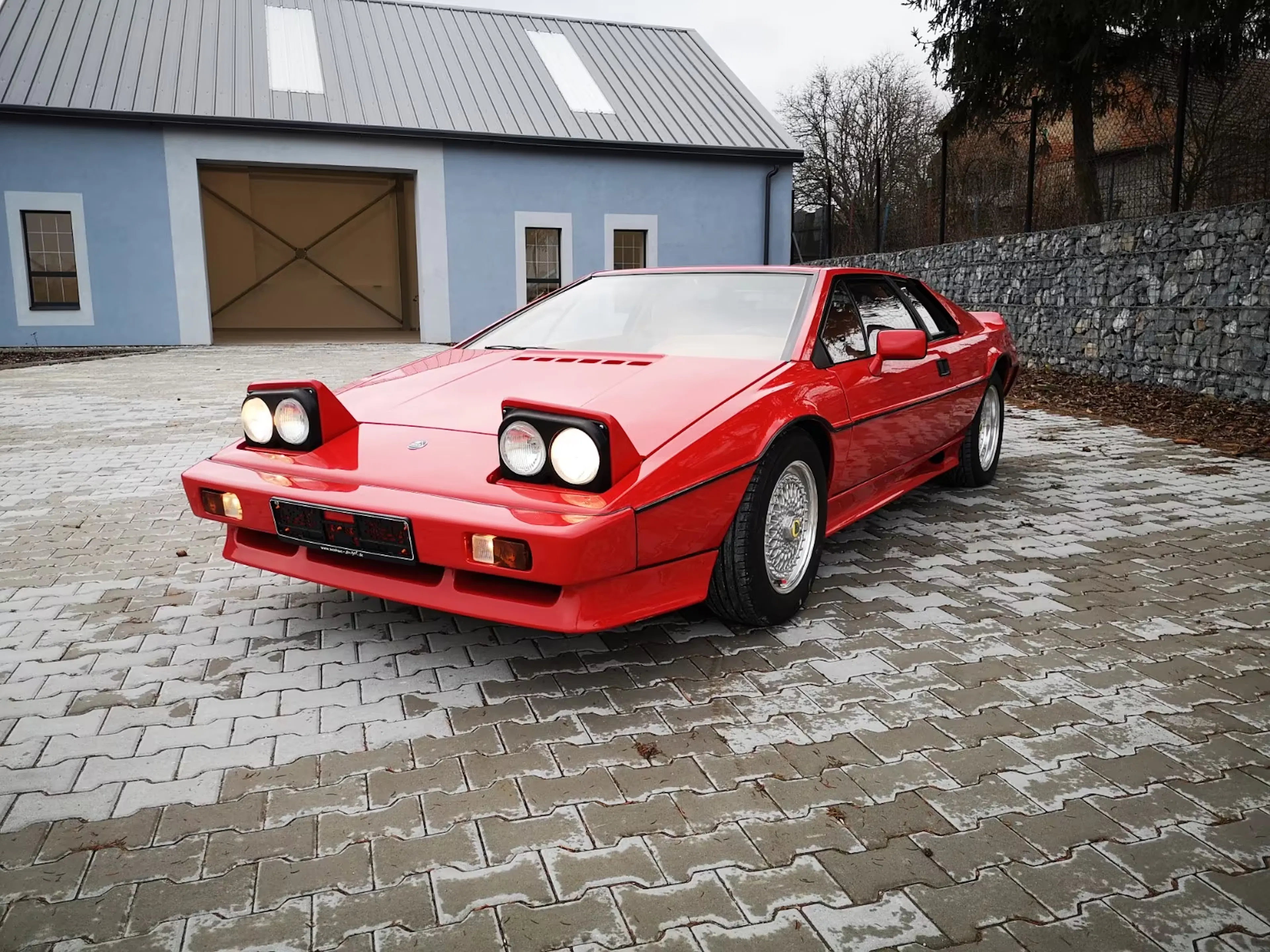 Ein roter Lotus Esprit steht in einer Hofeinfahrt.