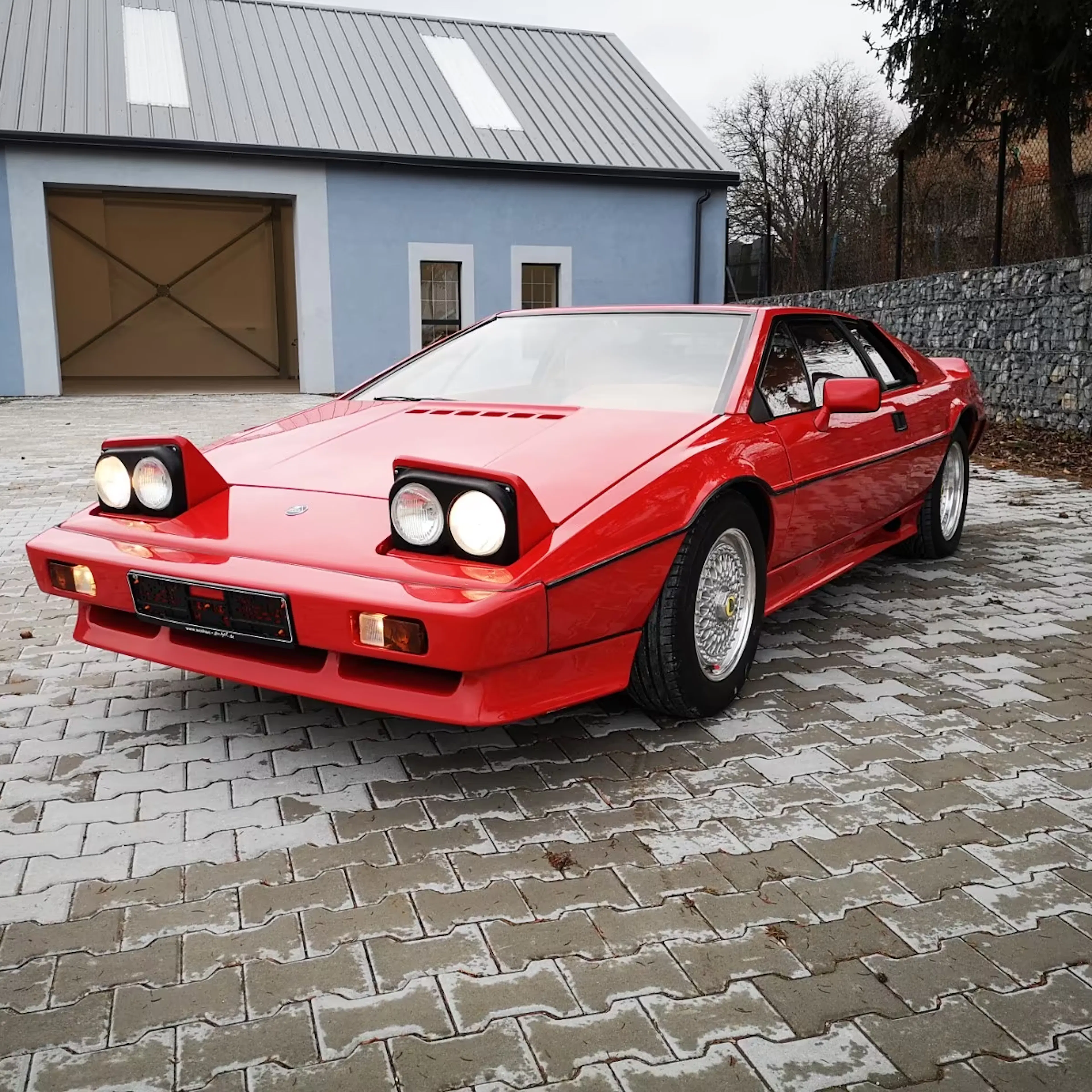 Ein roter Lotus Esprit steht in einer Hofeinfahrt.