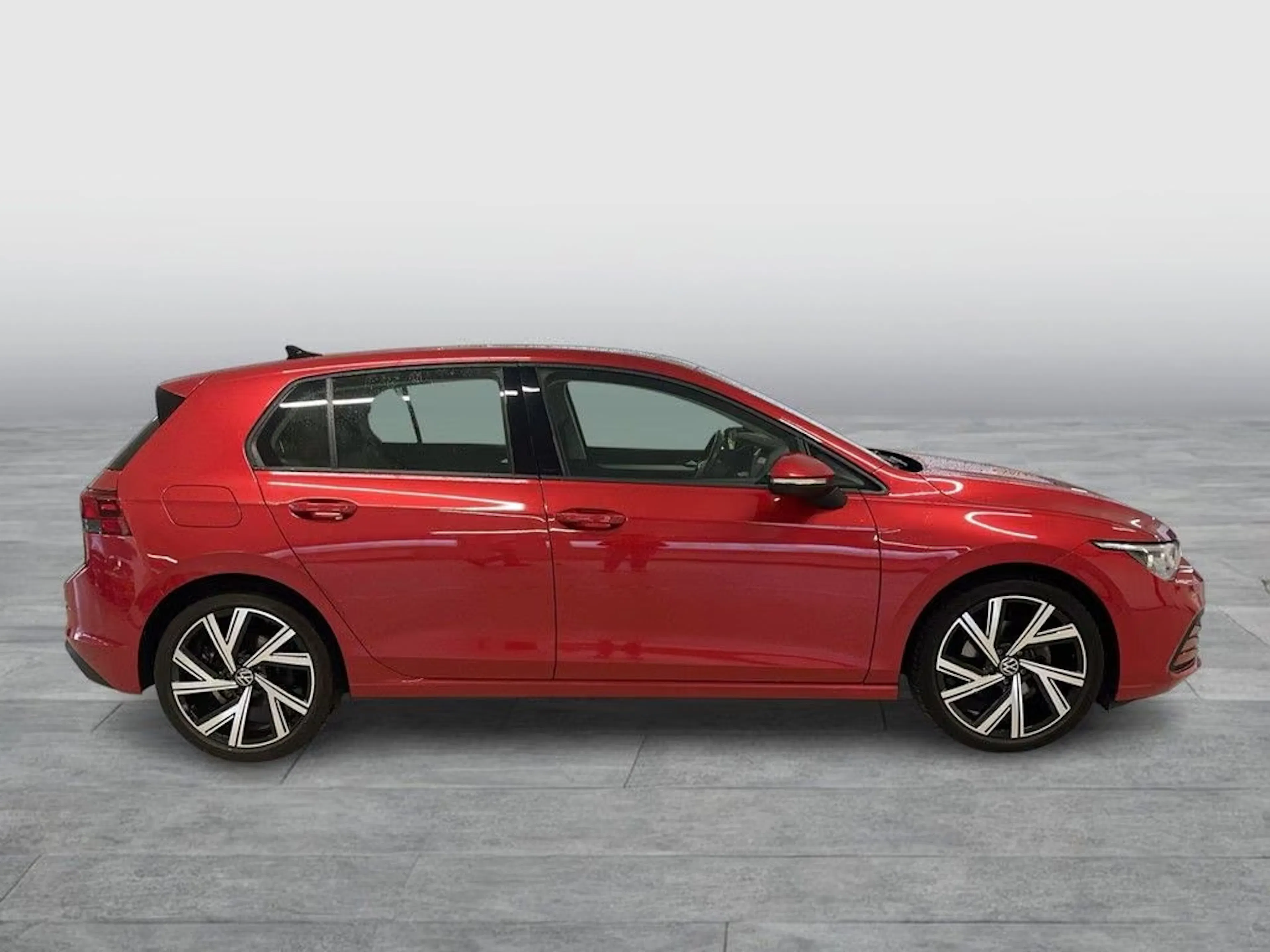 Ein roter VW Golf steht auf einer gepflasterten Fläche.