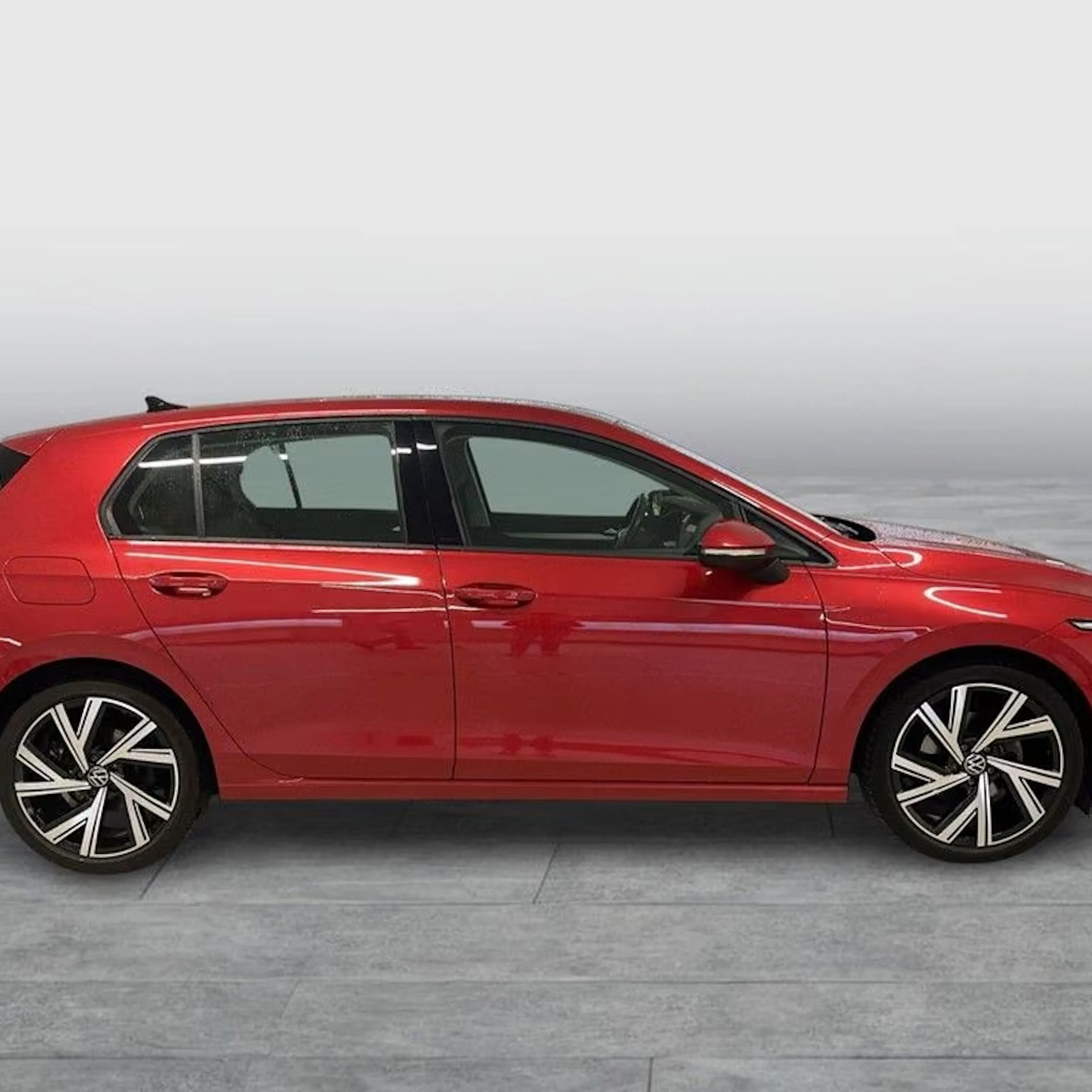 Ein roter VW Golf steht auf einer gepflasterten Fläche.