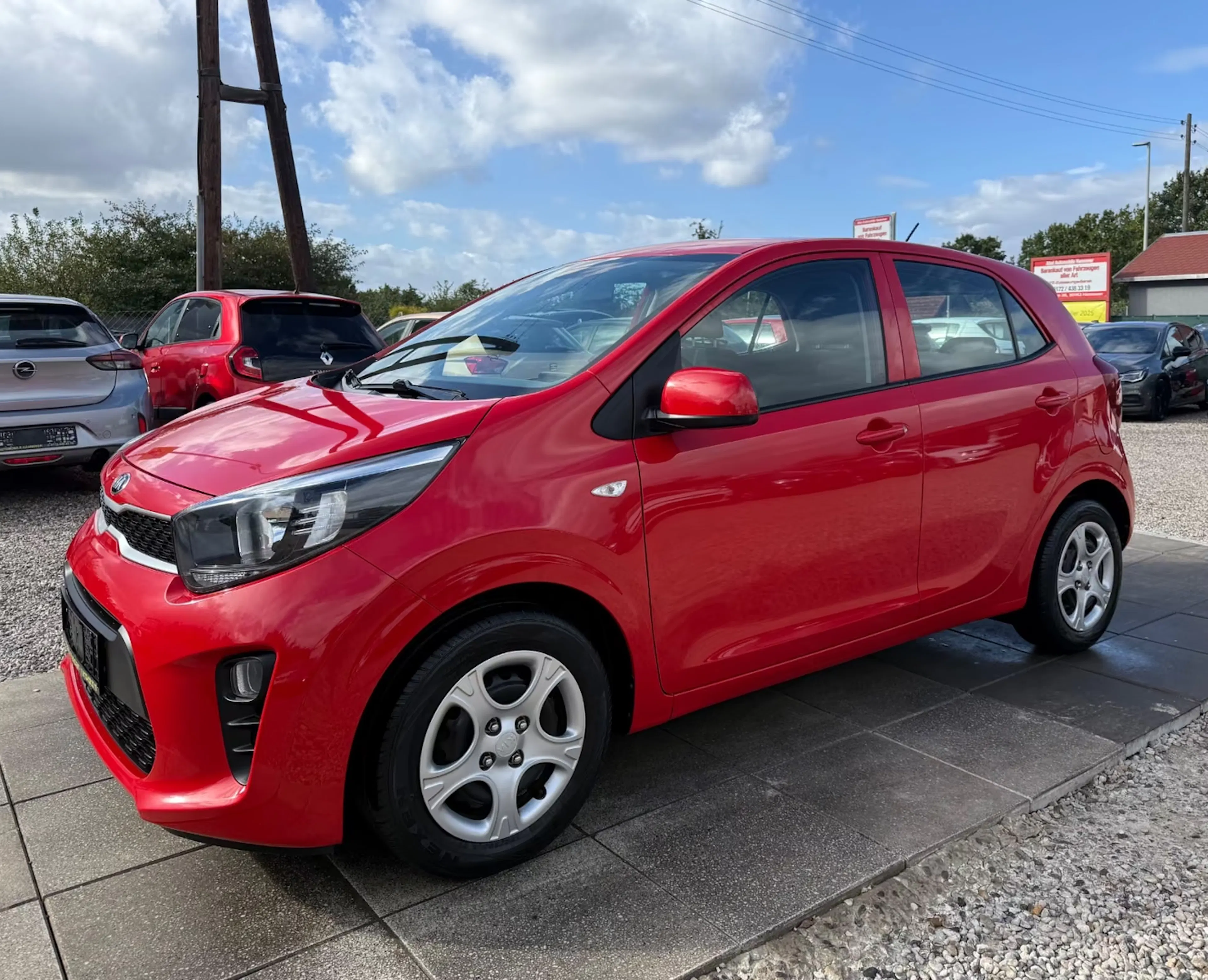 Ein roter Kia Picanto steht auf einer befestigten Fläche.