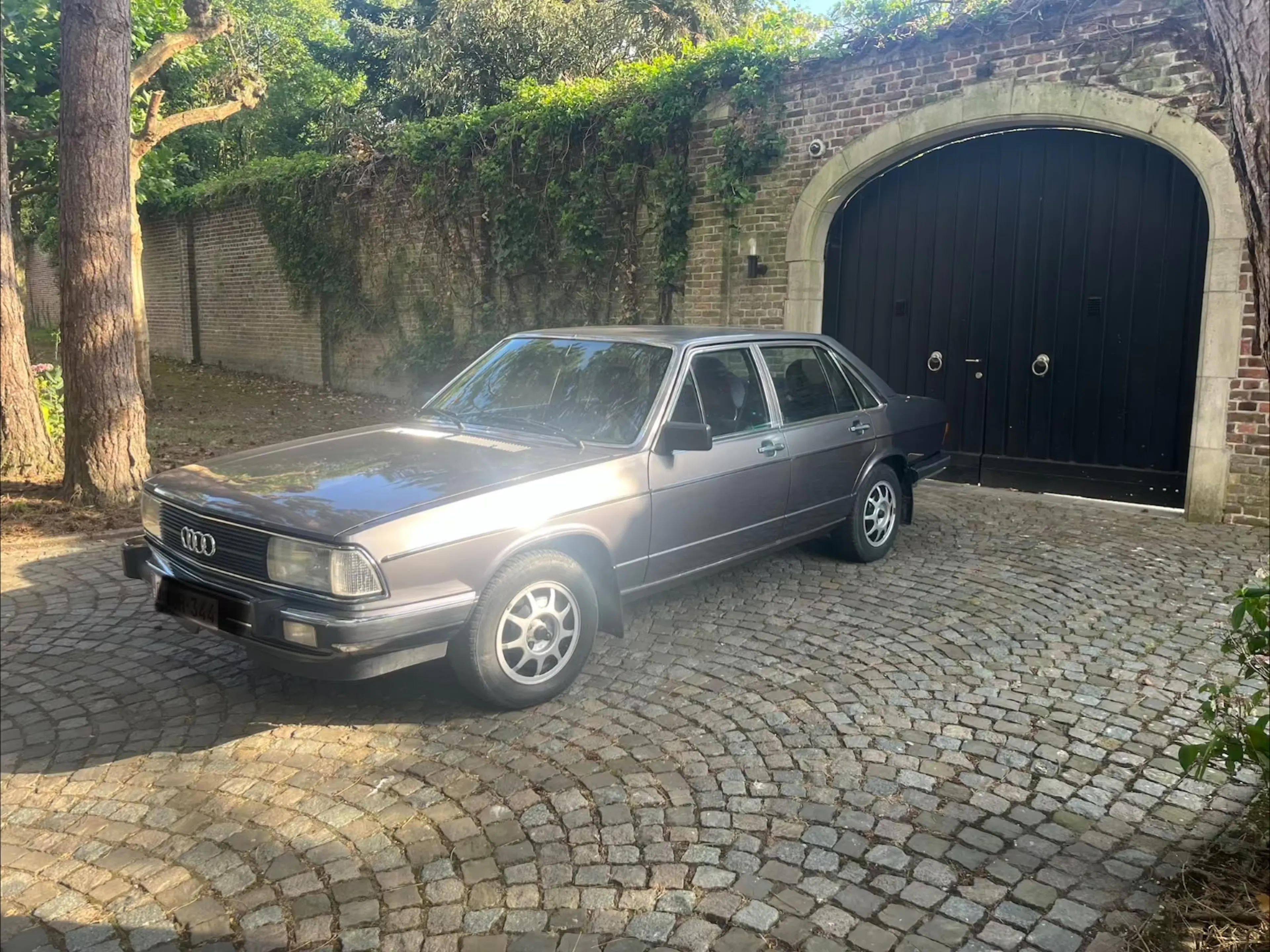 Grauer Audi 100 C2 vor Toreinfahrt