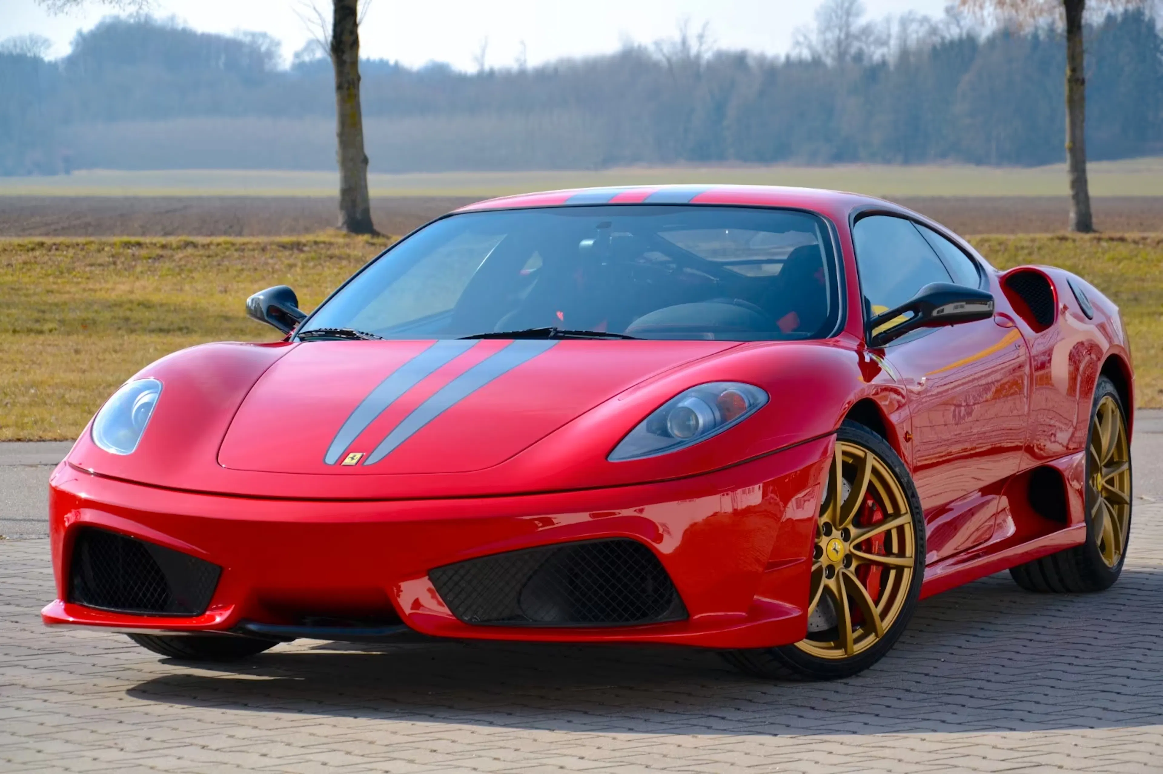 Ein roter Ferrari F430 steht auf einem Parkplatz.