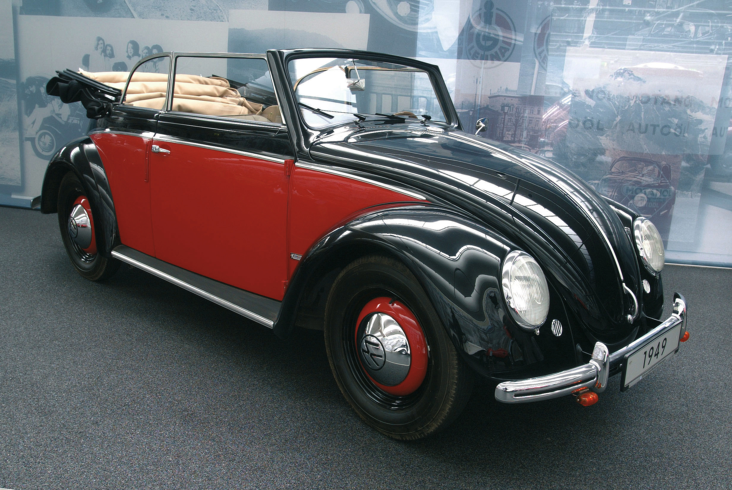 Zweifarbiger VW Käfer Cabriolet von 1949 in Schwarz und Rot in der Dreiviertel-Frontansicht, ausgestellt in einem Automobilmuseum.
