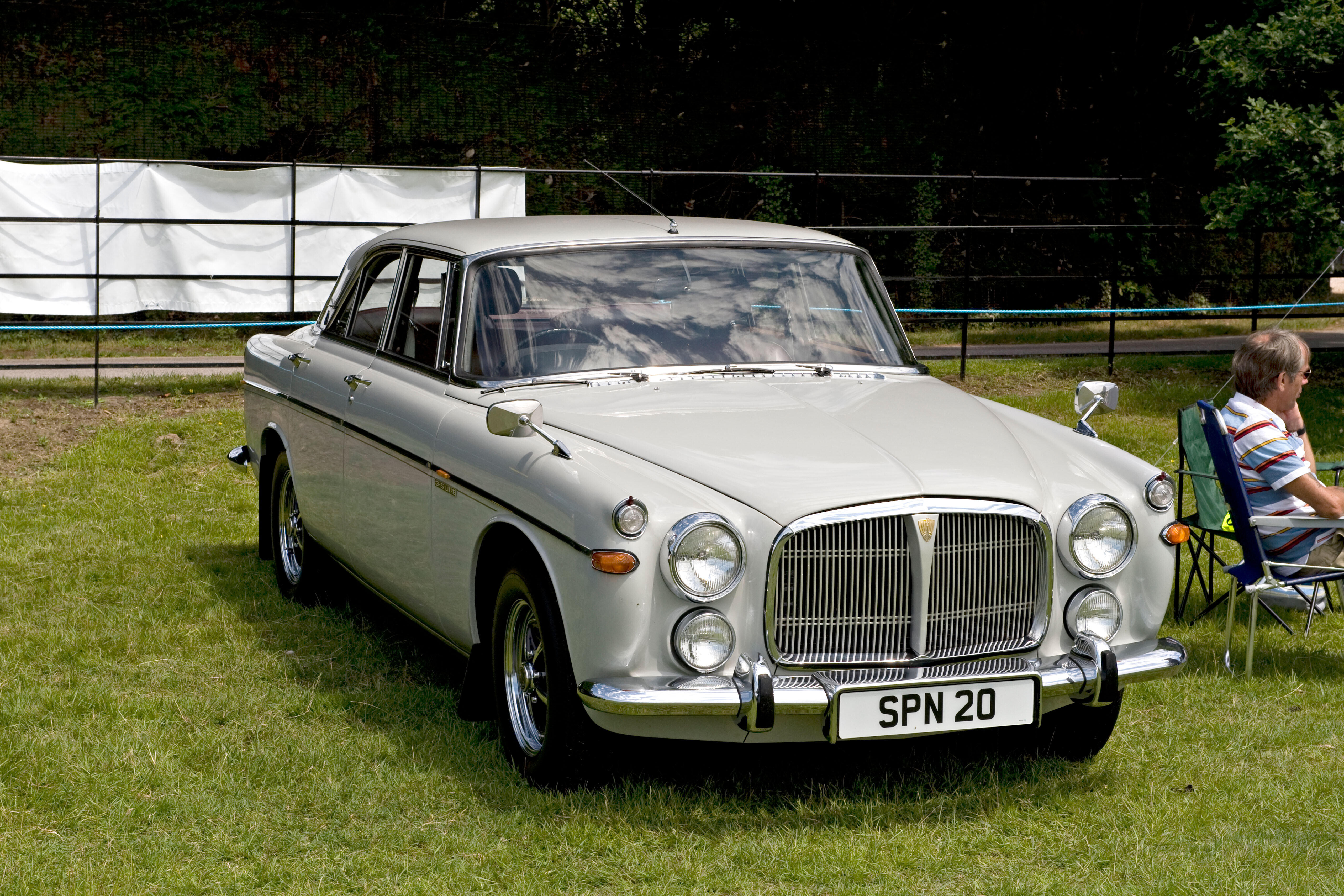 Hellgrauer Rover P5 in Frontansicht auf einer Wiese, geparkter Oldtimer bei einer Veranstaltung.