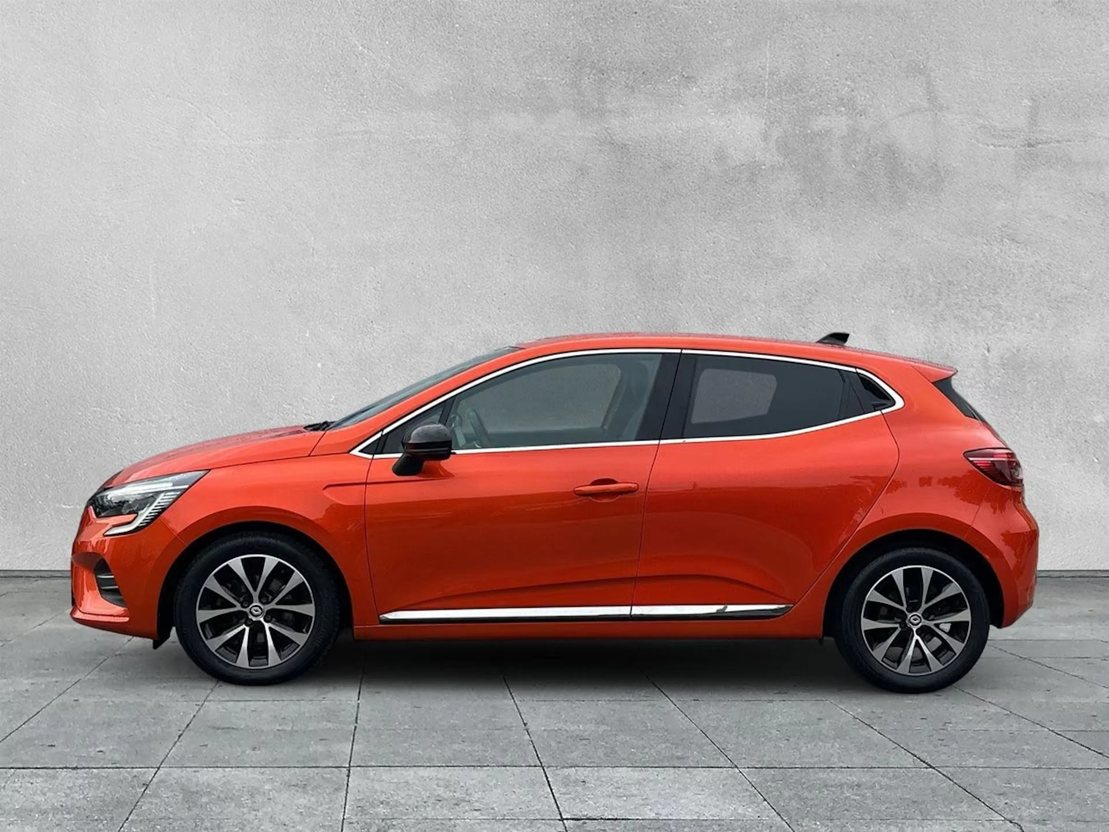 Ein roter Renault Clio E-Tech Full Hybrid steht auf einer gepflasterten Fläche.