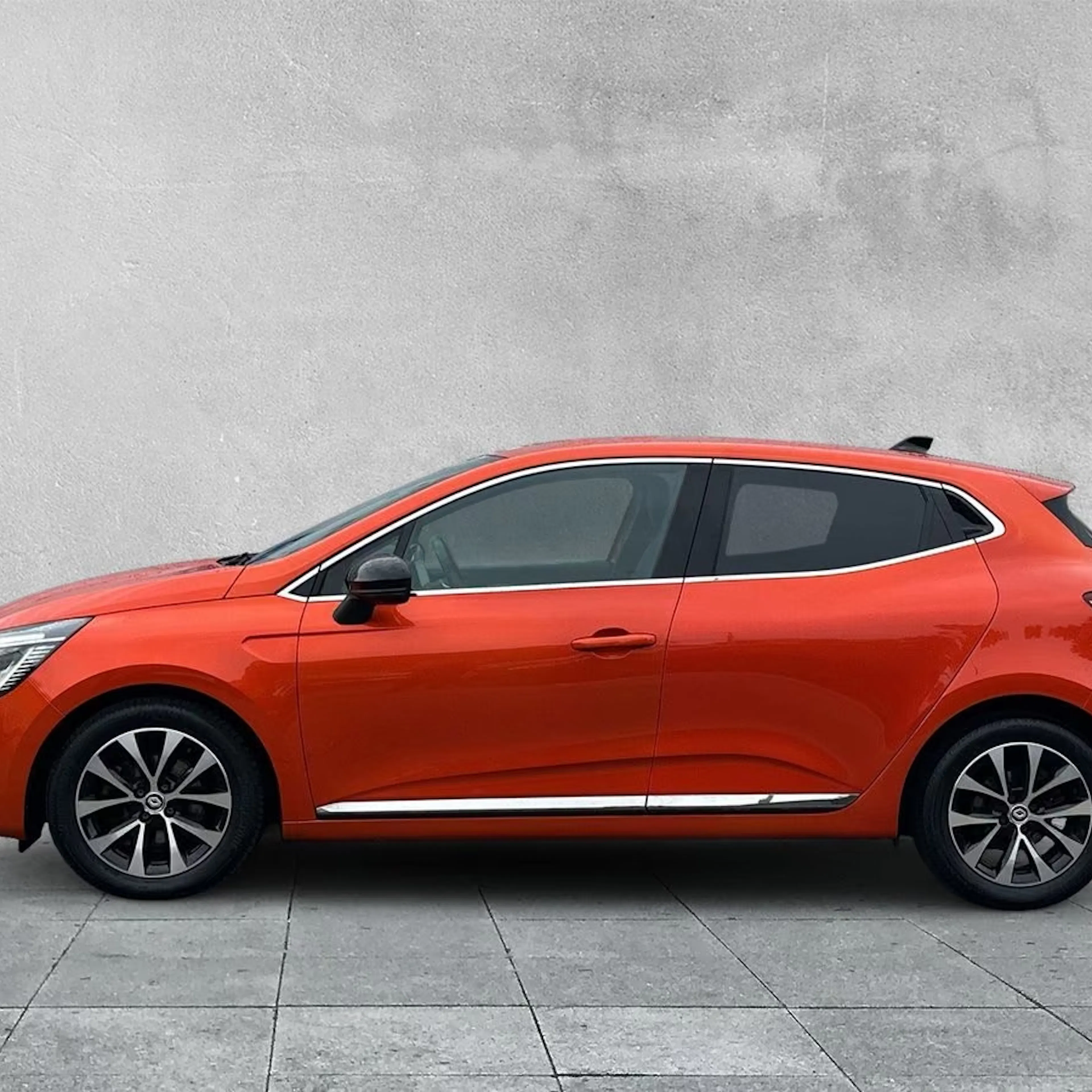 Ein roter Renault Clio E-Tech Full Hybrid steht auf einer gepflasterten Fläche.