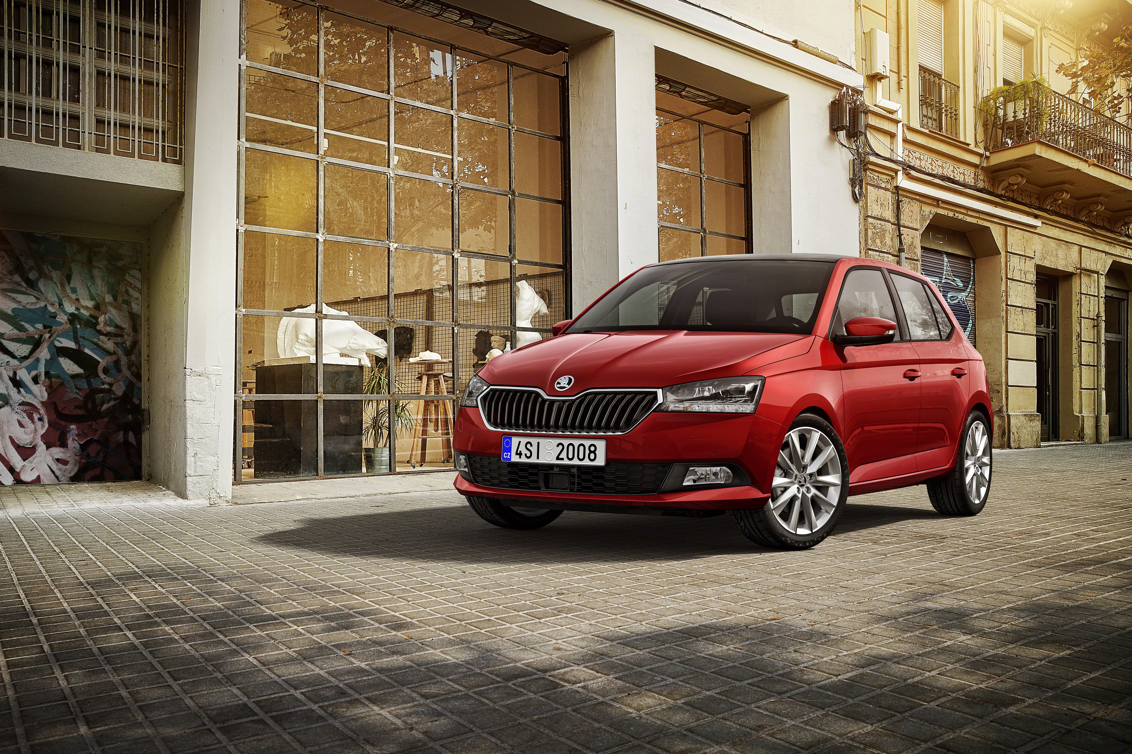 Roter Škoda Fabia III steht auf Kopfsteinpflaster vor einem Altbau mit großer Sprossenfassade.