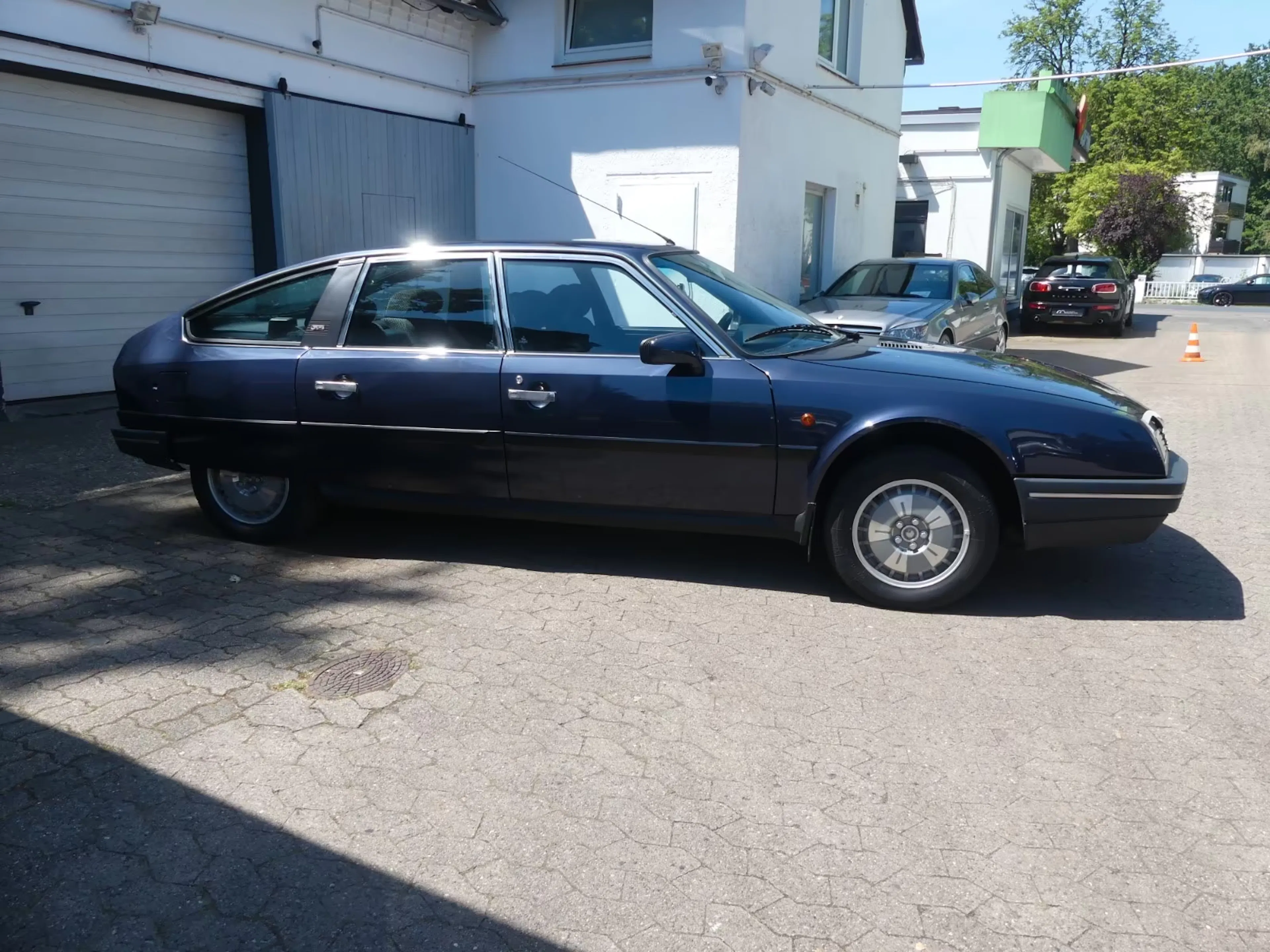 Ein dunkelblauer Citroën CX steht vor einer Garage.