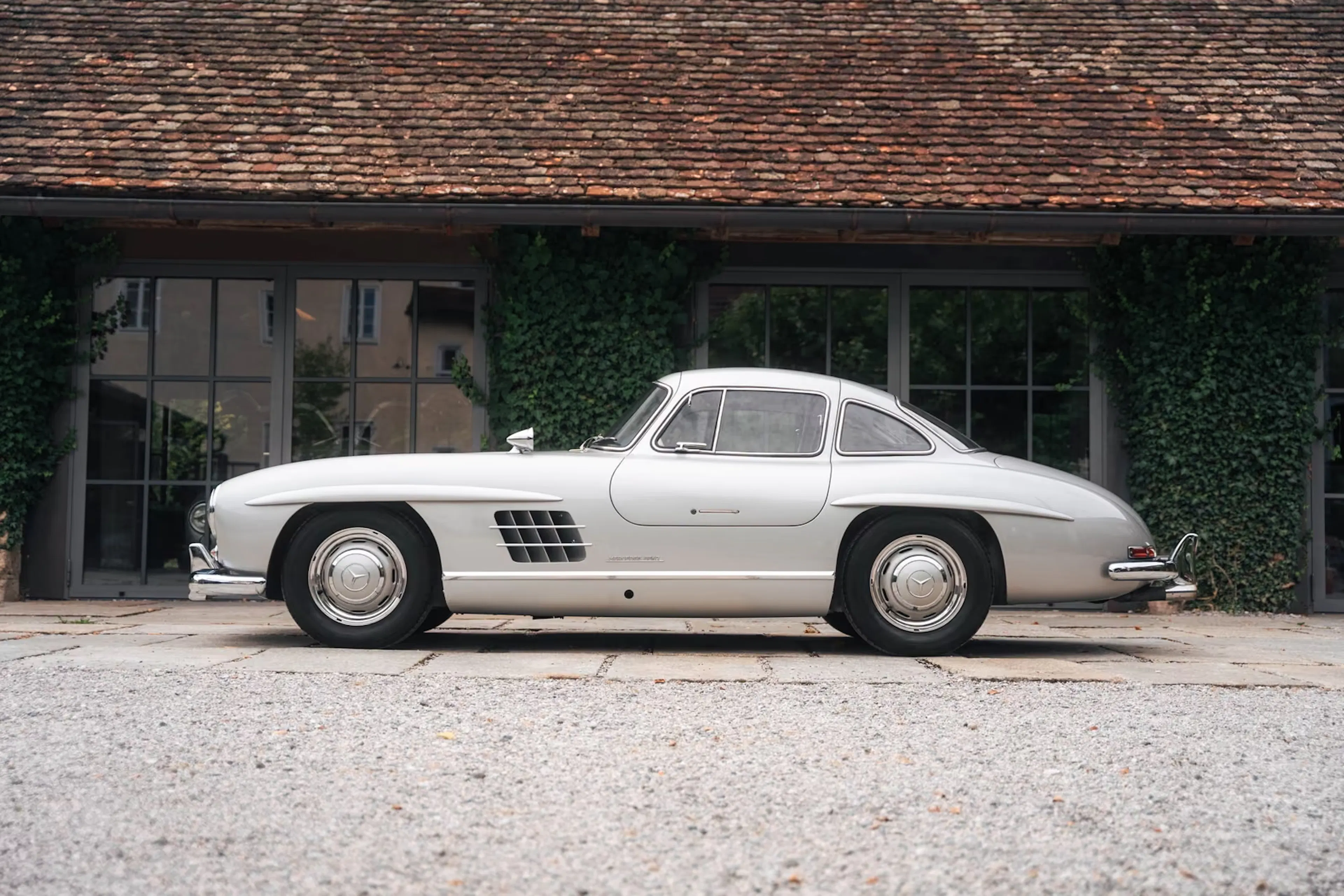 Silberner Mercedes 300 SL vor Anwesen