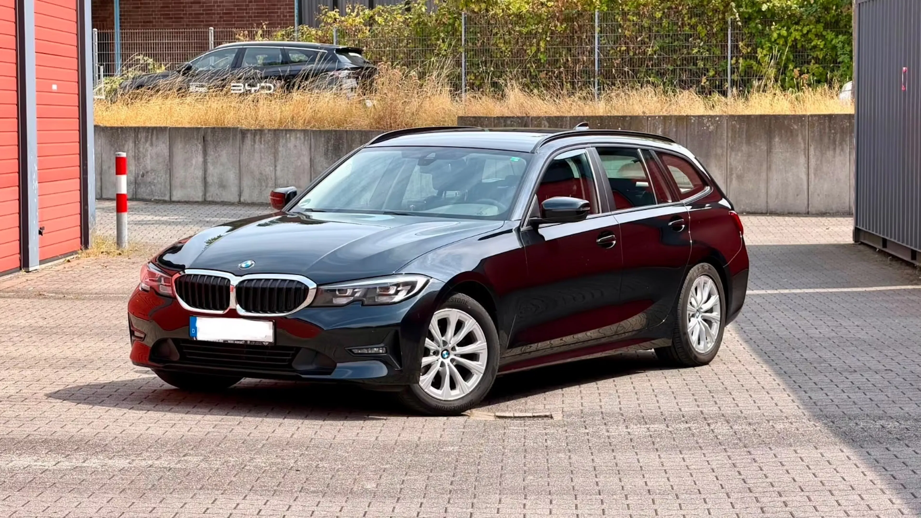Ein gebrauchter BMW 318 d Touring steht auf einer gepflasterten Fläche.