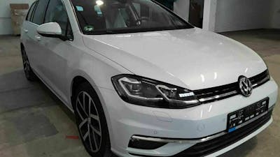 Ein weißer VW Golf 7 steht in einer leeren Halle