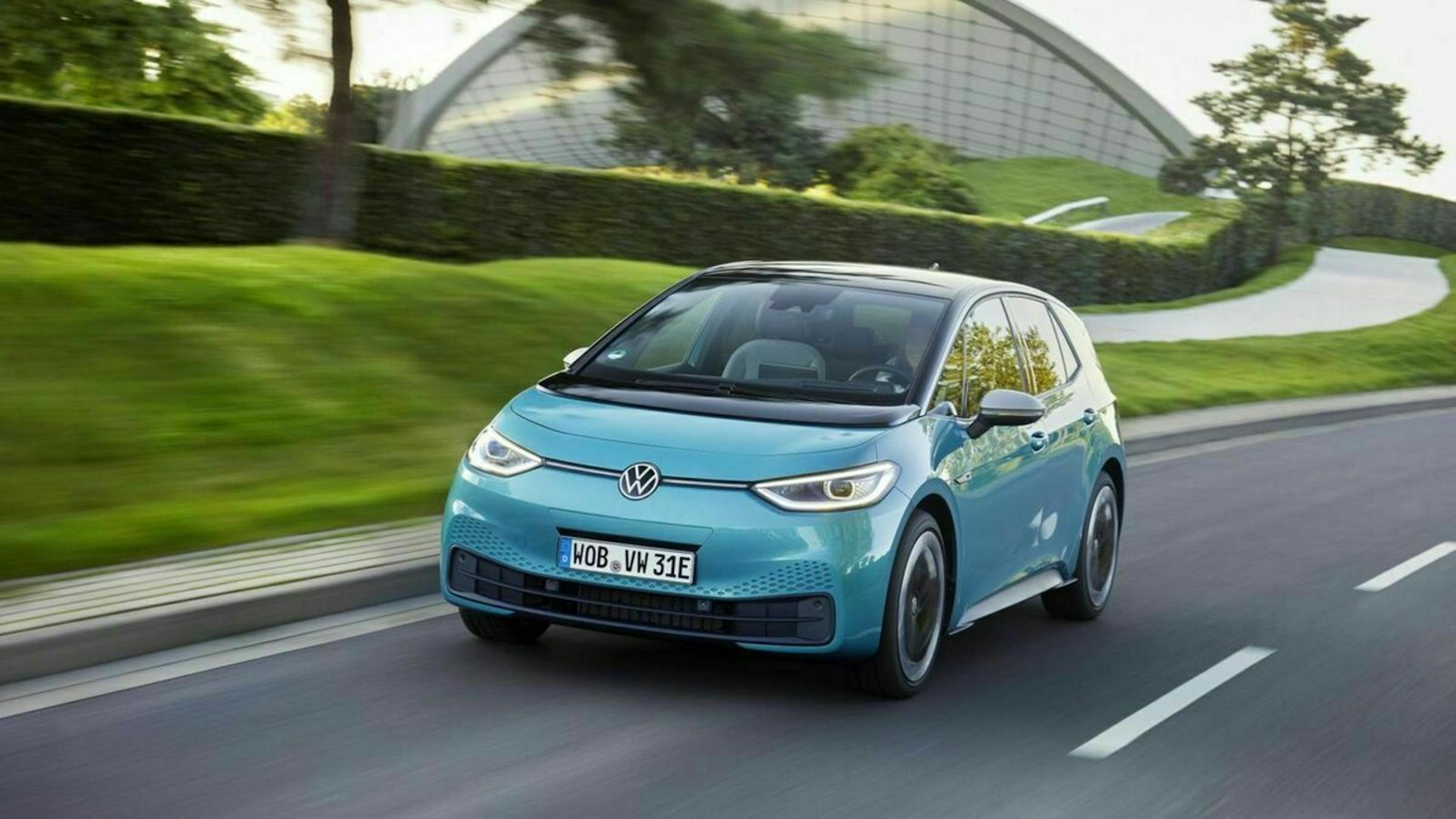 Ein türkiser VD ID.3 fährt an einem Stadtpark vorbei