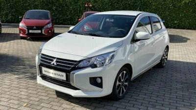 Ein weißer Mitsubishi Space Star steht auf einem Parkplatz.