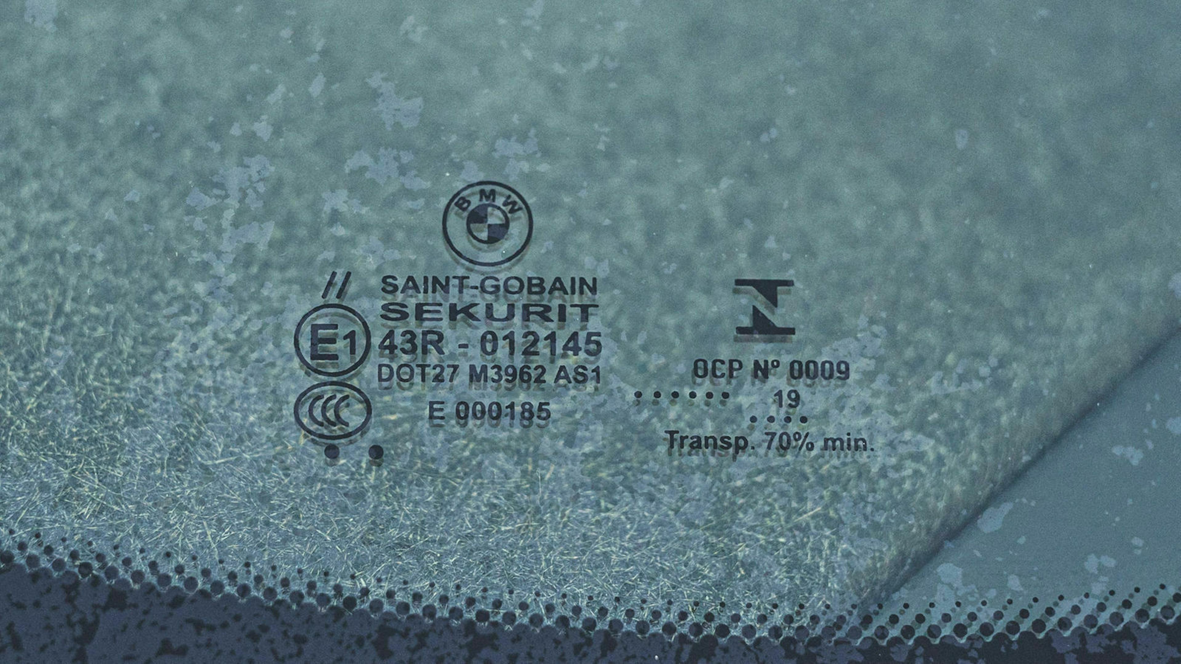 Das Bild zeigt einen Stempel auf einer Windschutzscheibe, das das Produktionsjahr der Scheibe angibt