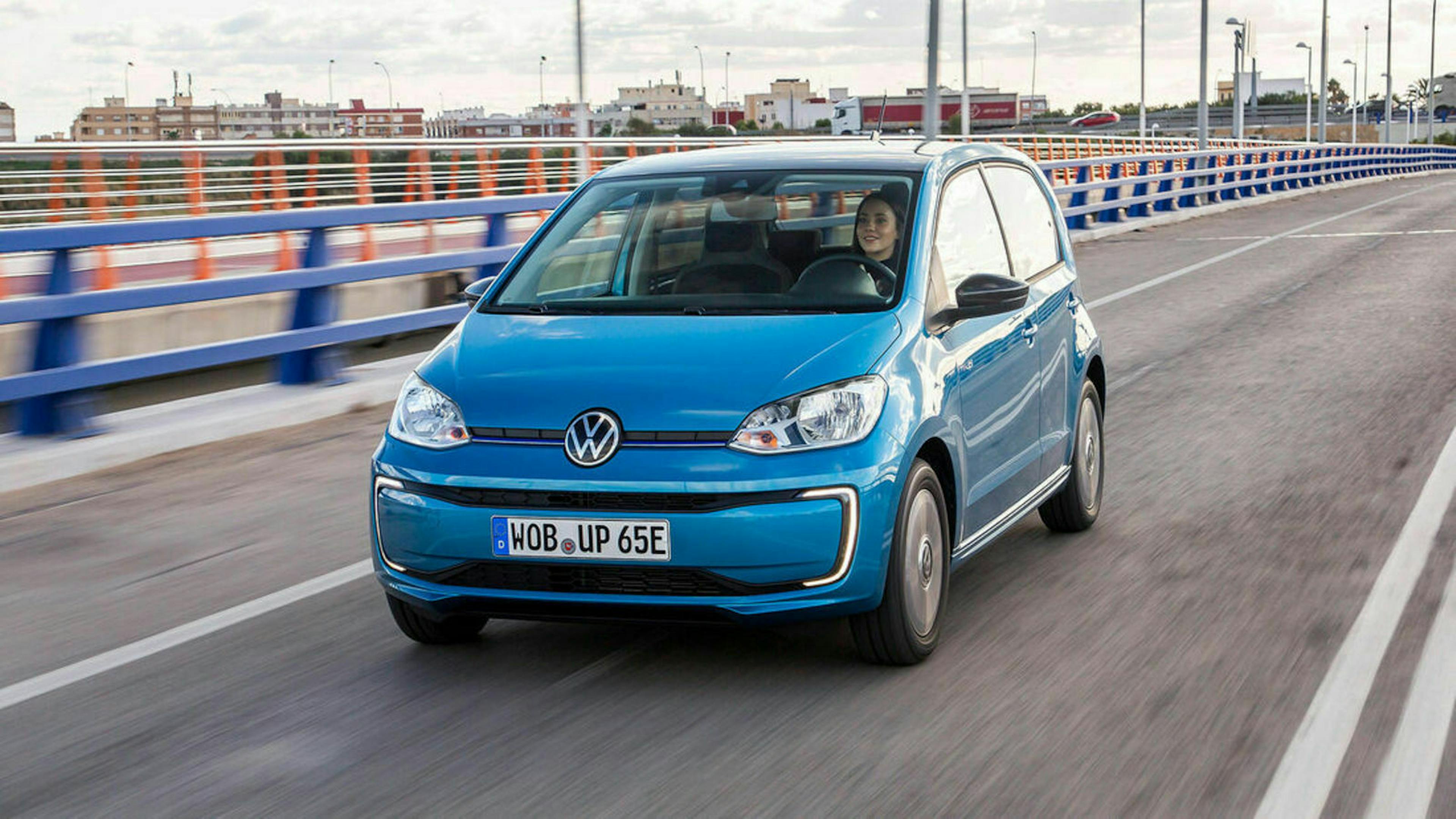 Ein blauer VW e-Up fährt über eine Brücke.