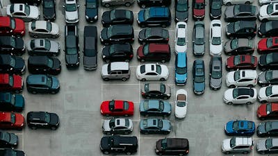 Draufsicht auf einen Parkplatz, auf dem PKWs in verschiedenen Farben stehen