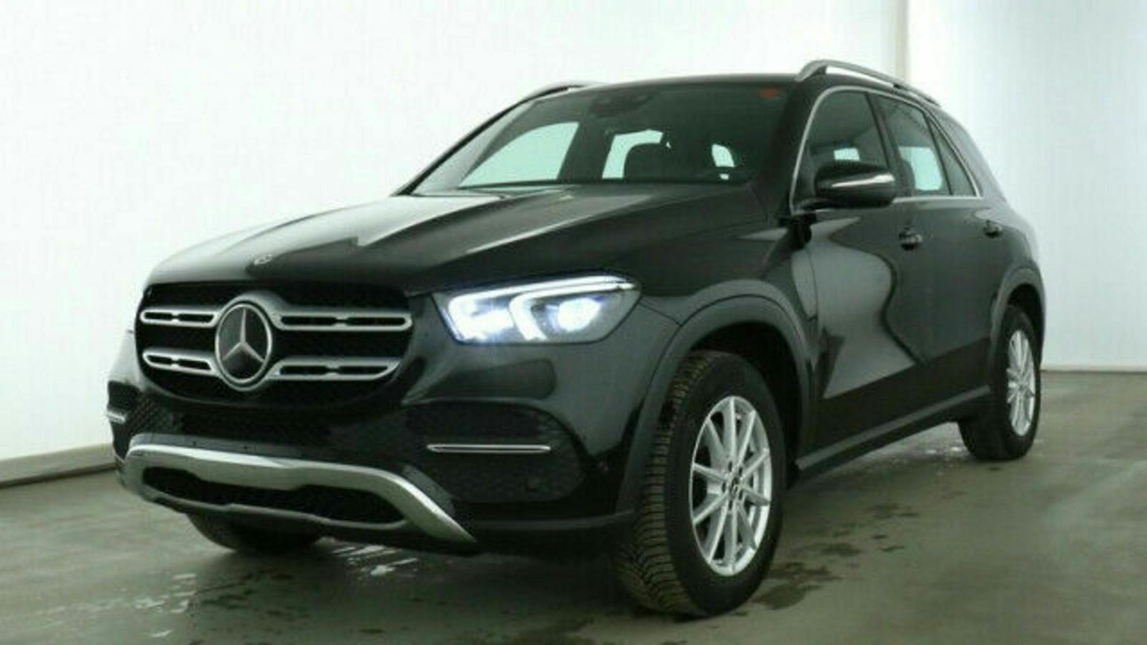 Schwarzer SUV der Marke Mercedes-Benz steht in einem hellen Raum. Vorderansicht mit sichtbaren Scheinwerfern und Markenemblem.