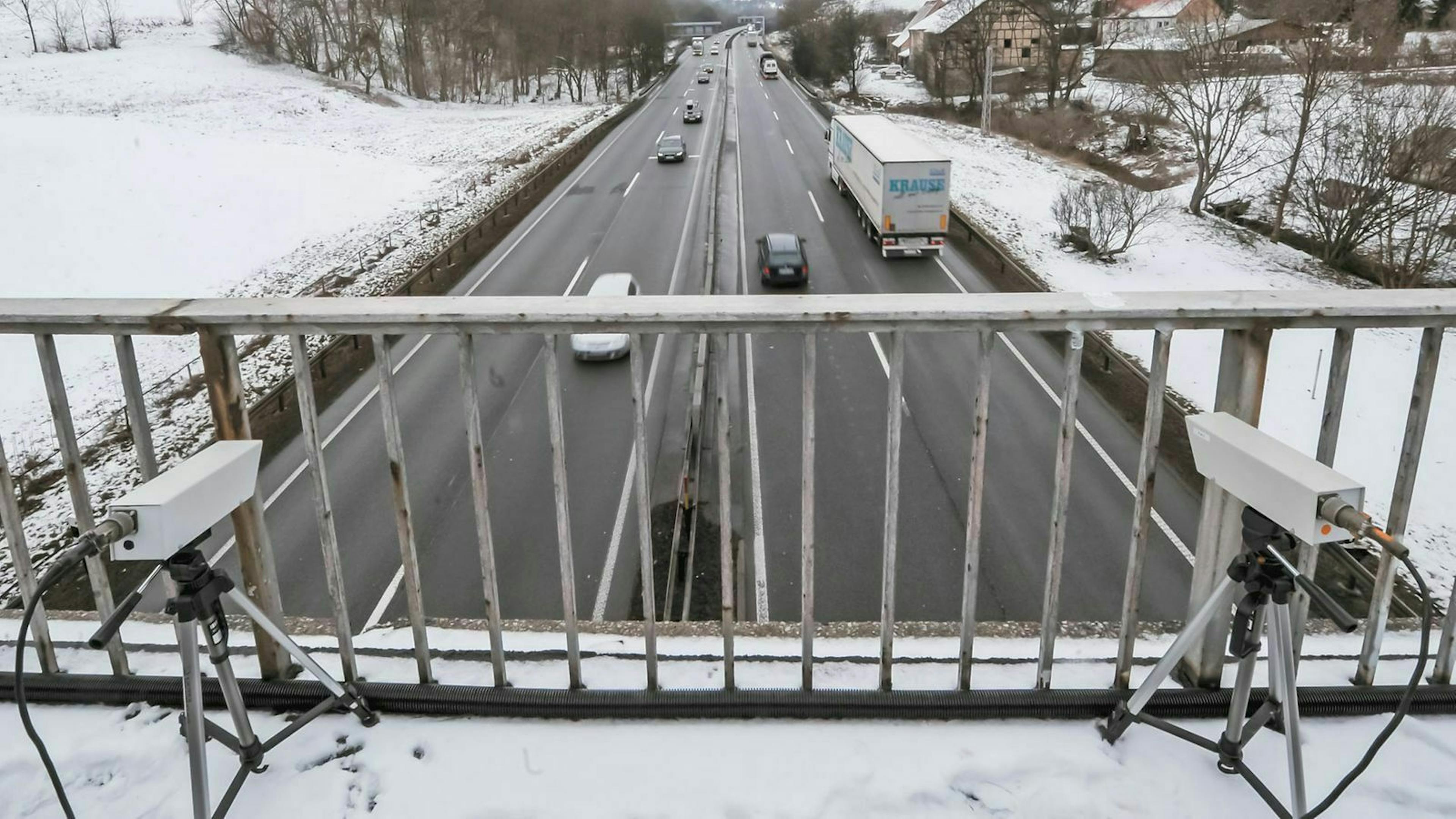 Zwei Messgeräte sind auf einer Brücke aufgebaut. Im Hintergund fahren Autos auf einer Autobahn