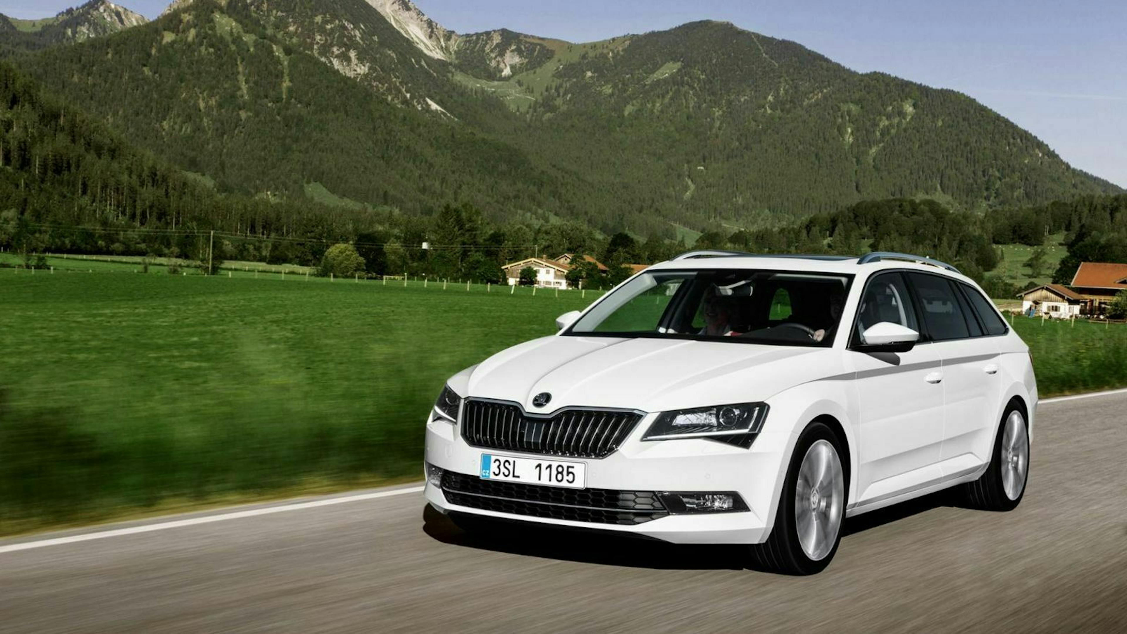 Ein weißer Skoda Superb fährt eine Landstraße entlang