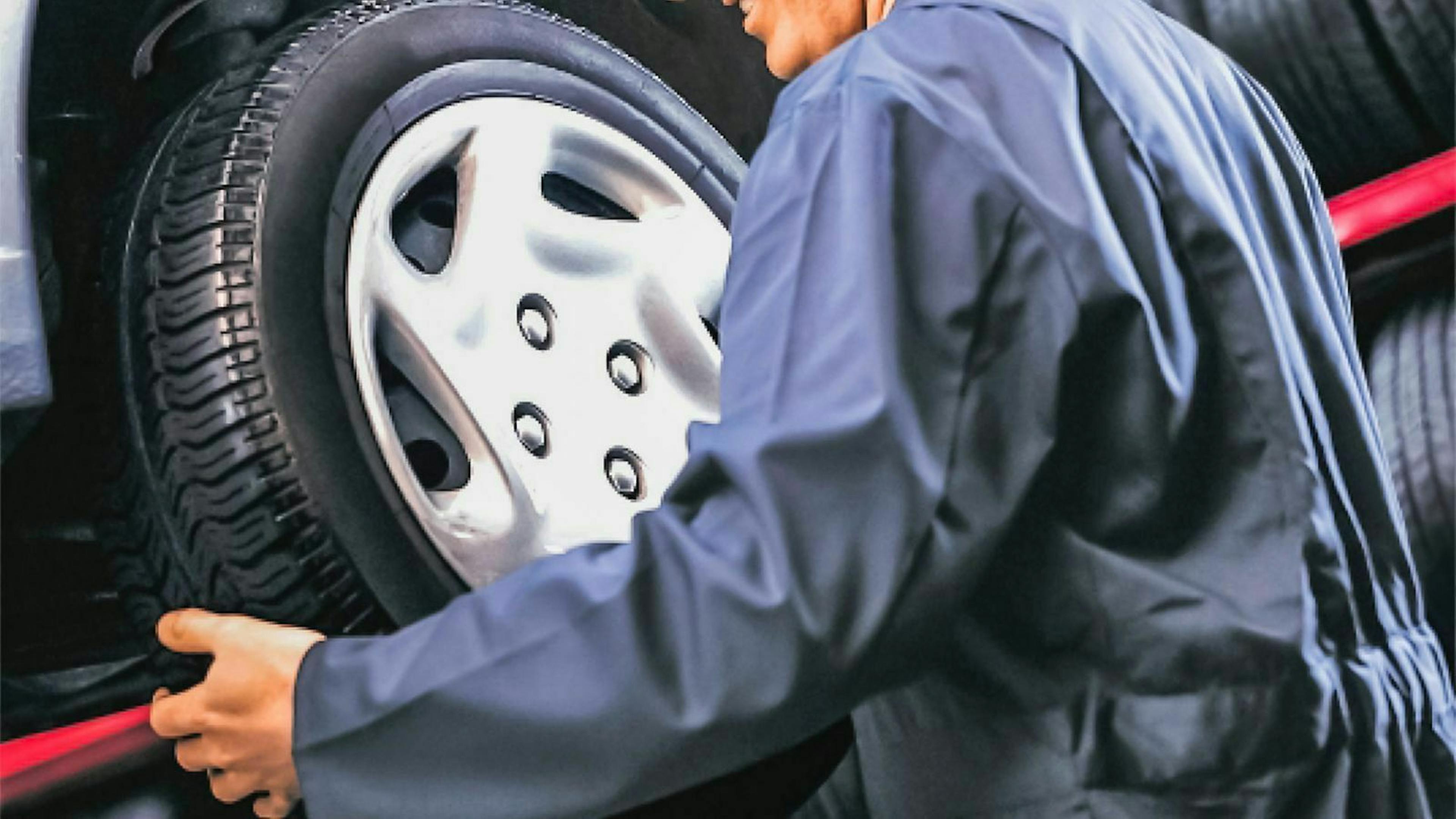 Ein Mechaniker nimmt ein Rad eines Autos ab. 