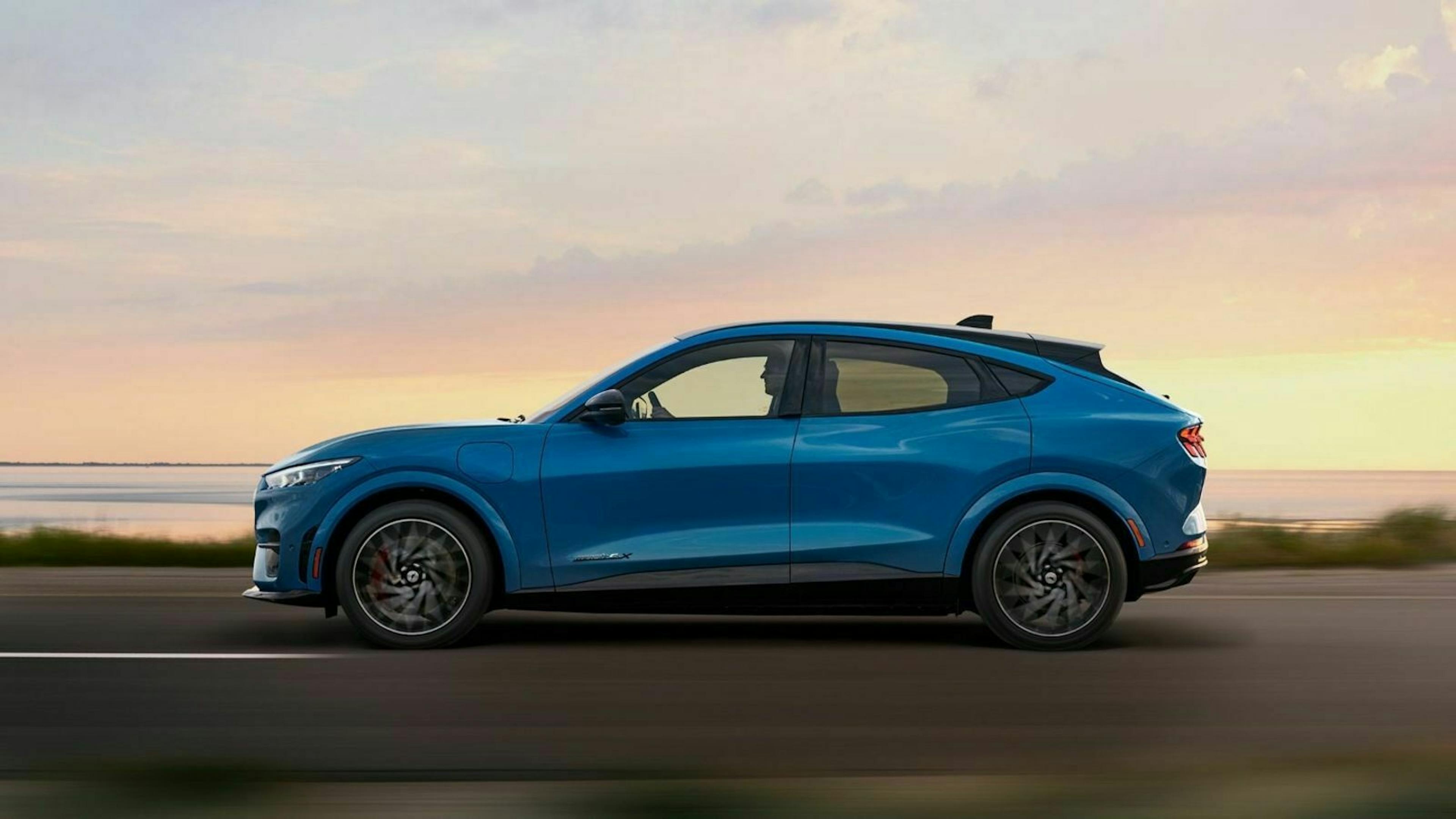 Ein blauer Ford Mustang Mach E fährt eine Landstraße entlang