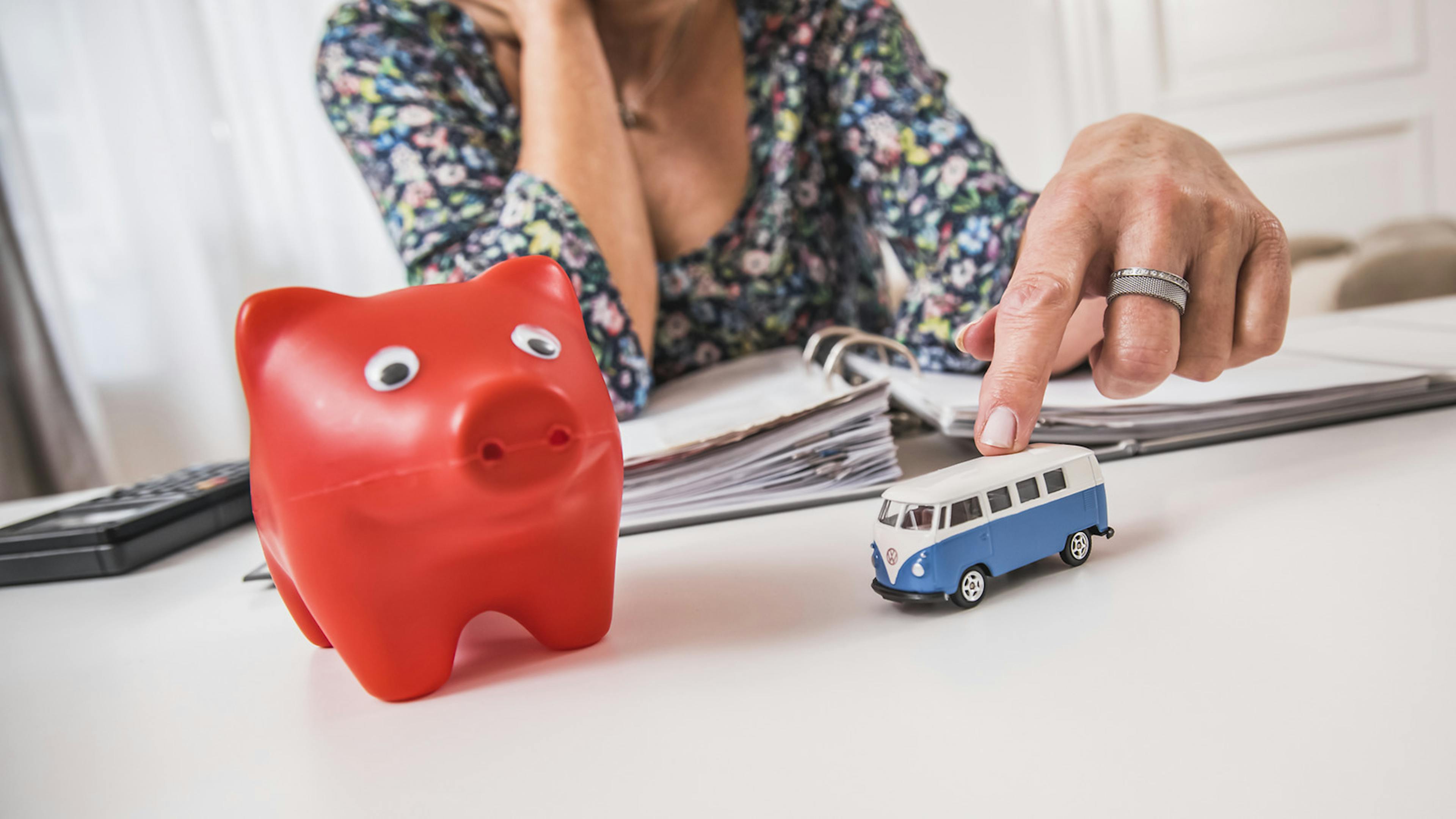 Ein rotes Sparschwein steht auf einem weißen Tisch