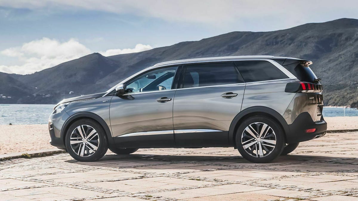Ein silbergrauer Peugeot 5008 parkt an einer Hasfenkante.