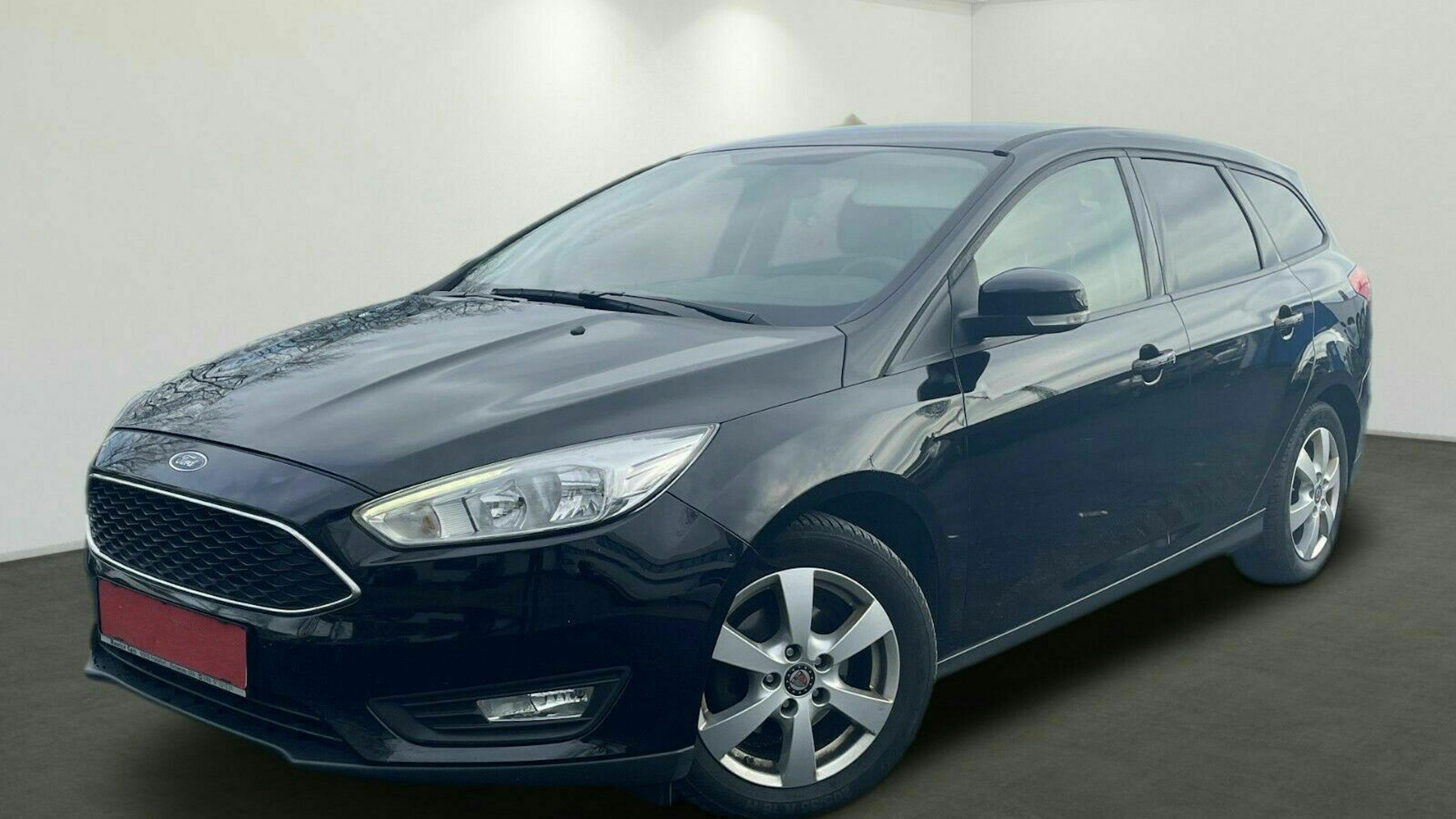 Ein schwarzer Ford Focus Turnier steht vor einer weißen Wand