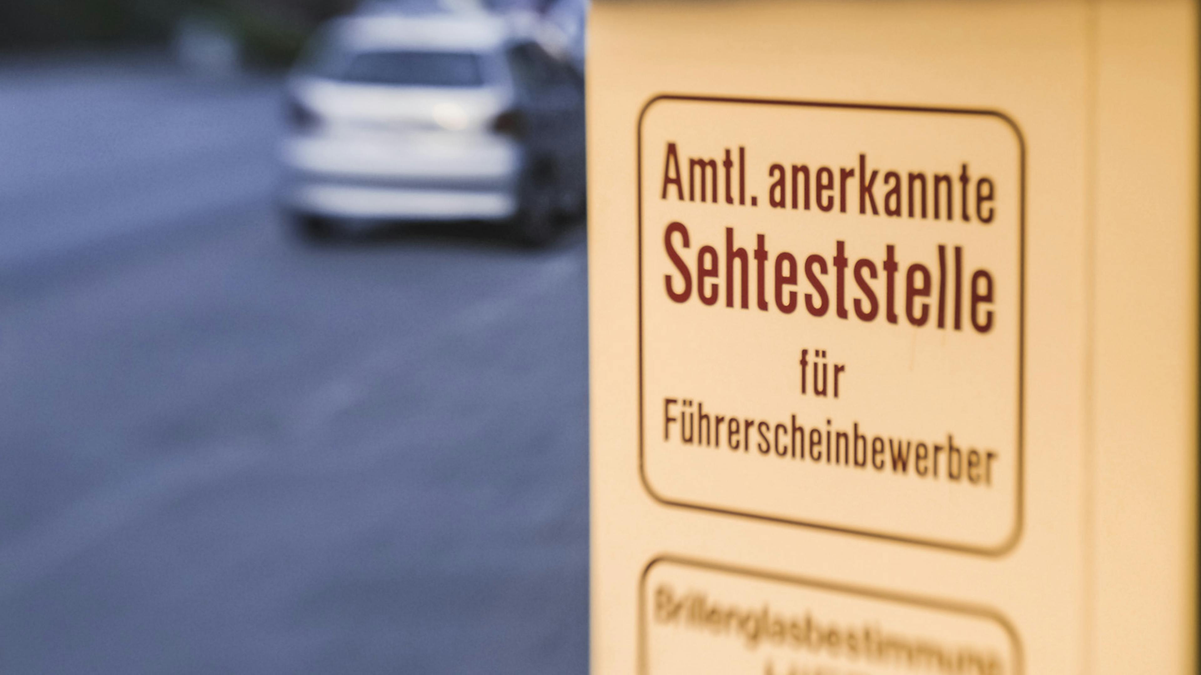 Ein Schild mit der Aufschrift "Amtl. anerkannte Sehteststelle" steht an einer Straße 