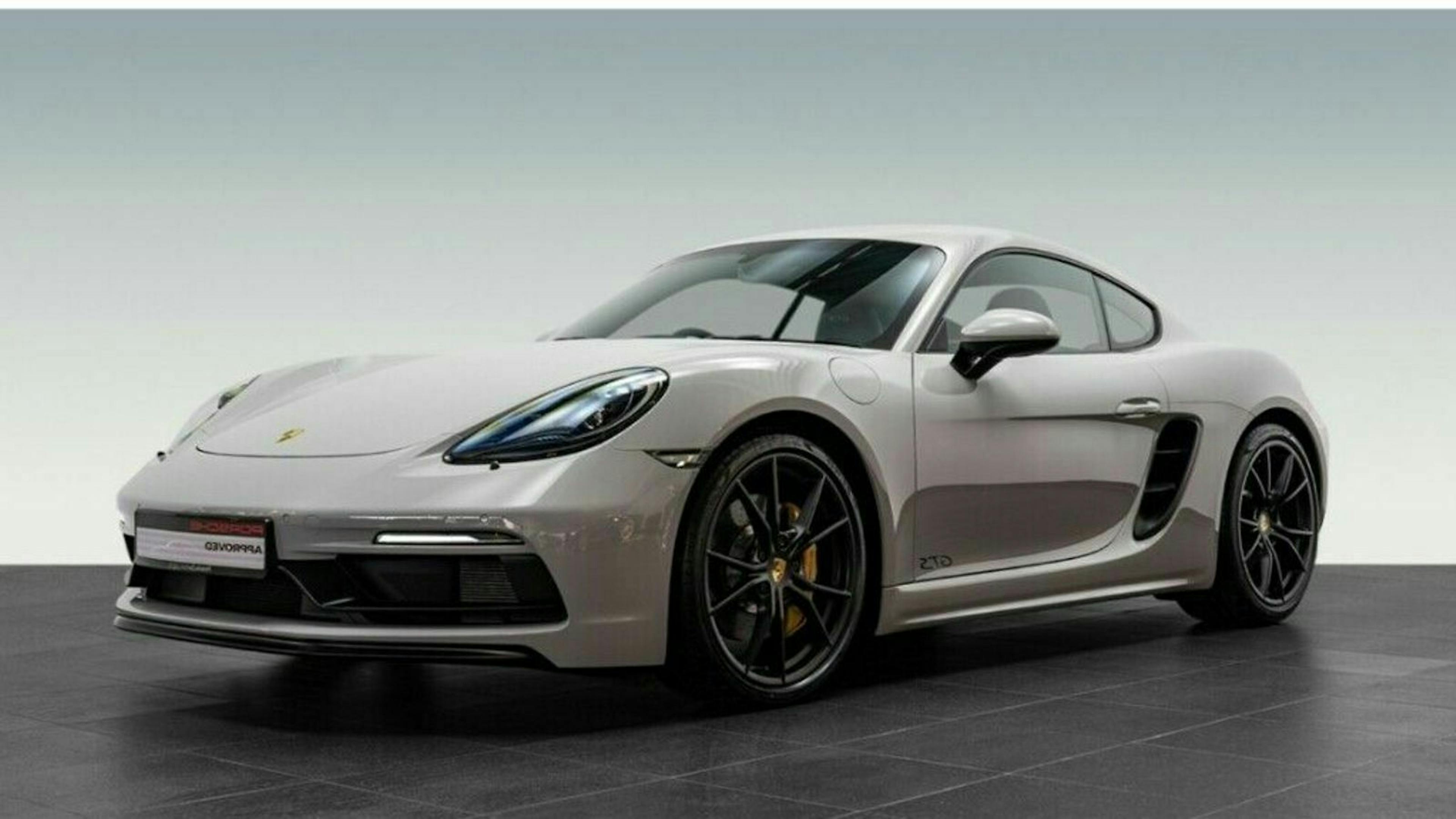 Grauer Sportwagen, seitliche Frontansicht auf schwarzem Boden. Elegantes Design mit großen Felgen und markanter Front.