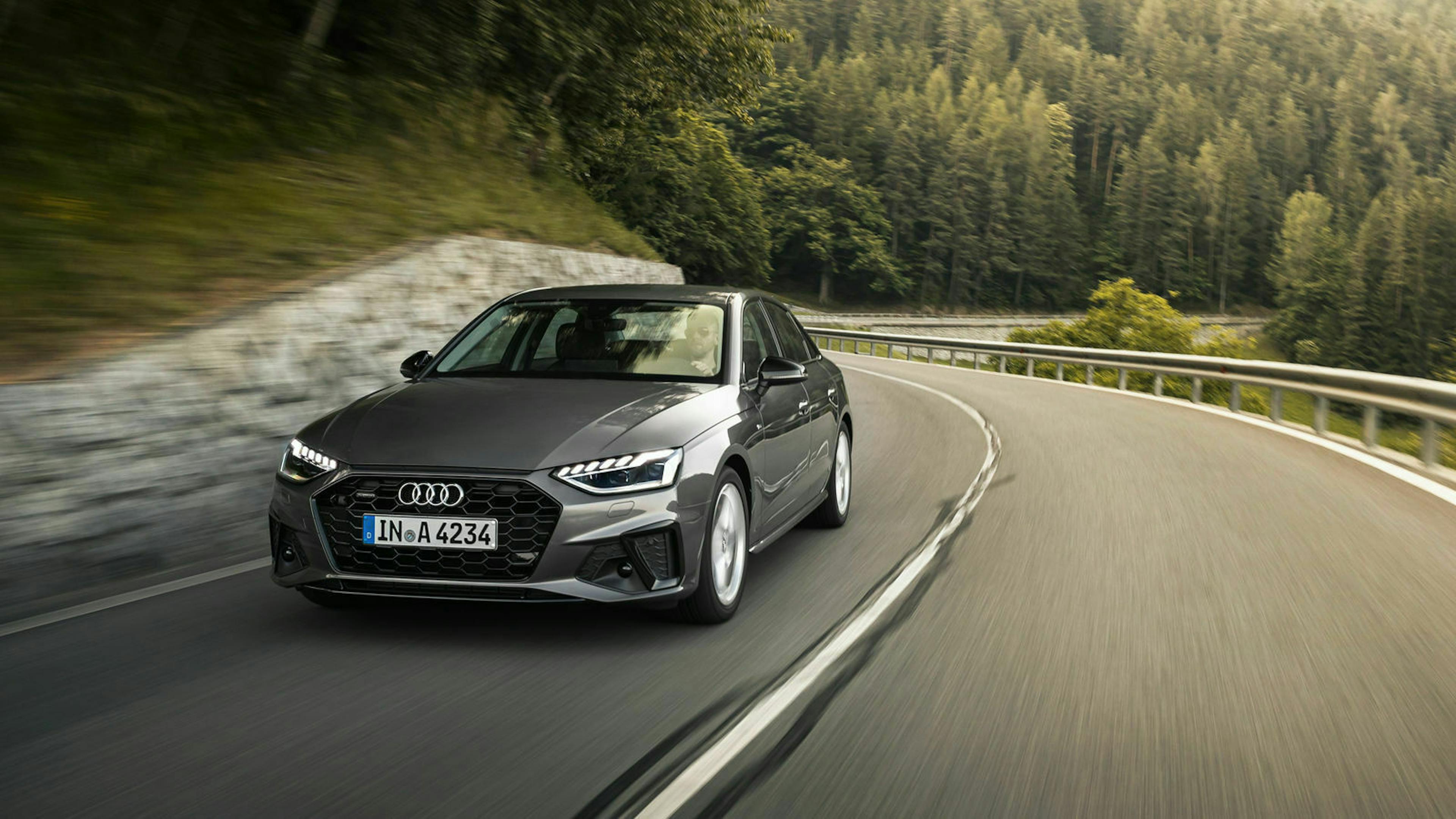 Ein dunkelgrauer Audi A4 fährt eine kurvige Bergstraße entlang