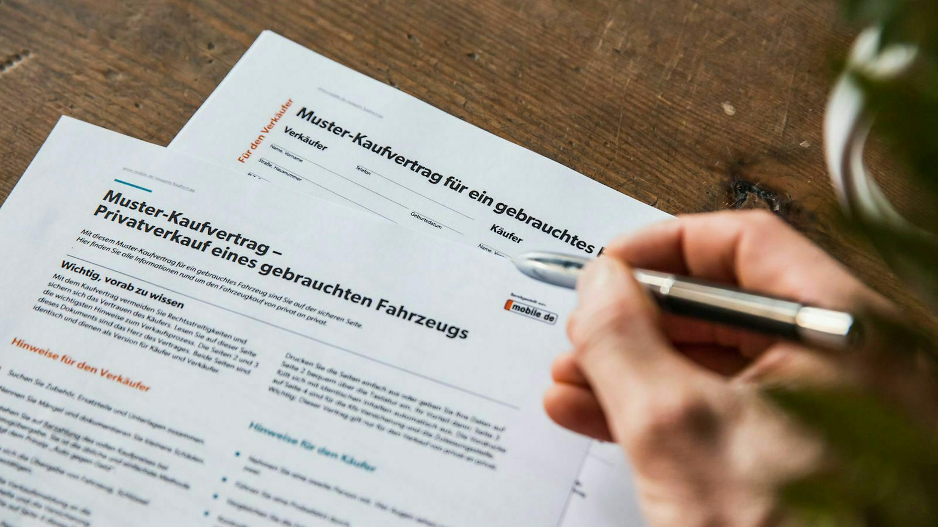 Jemand füllt den mobile.de Musterkaufvertrag für ein Gebrauchtfahrzeug aus. 