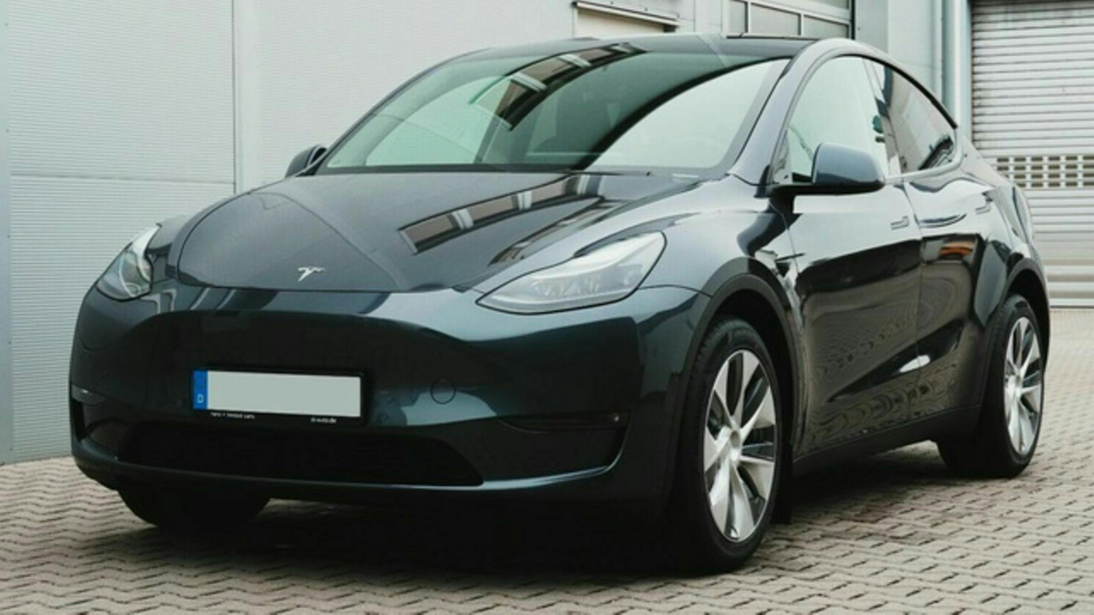 Ein schwarzer Tesla Model Y steht vor einem grauen Gebäude