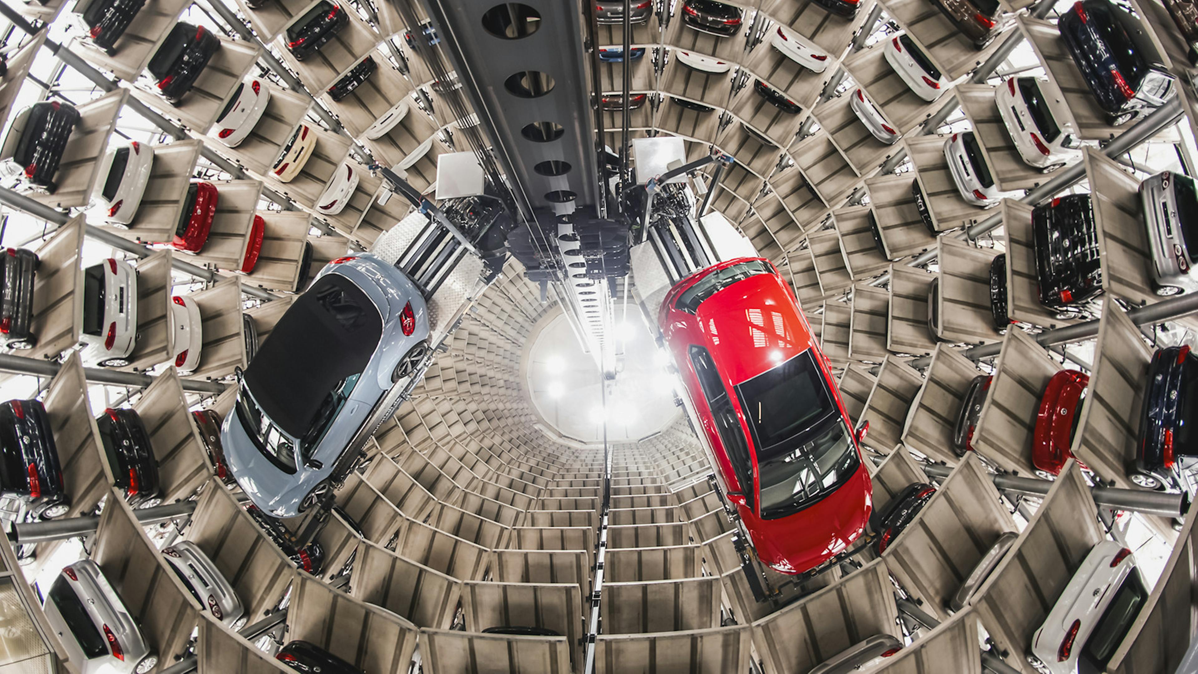 Zwei Autos schweben an einer Hebevorrichtung durch ein Auto-Hochregallager.