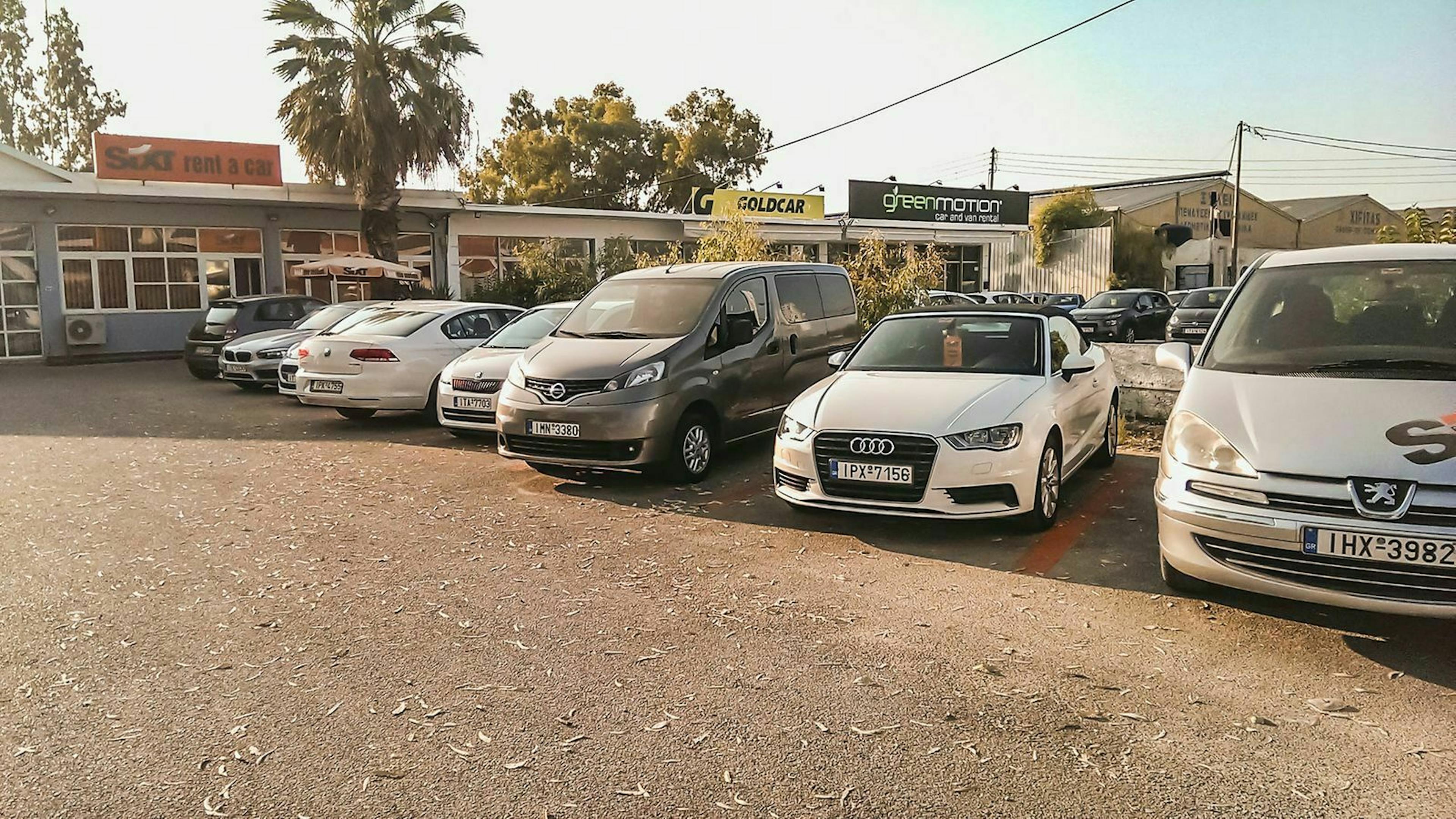 Mietwagen stehen an einem Urlaubsort auf dem Parkplatz einer Autovermietung.