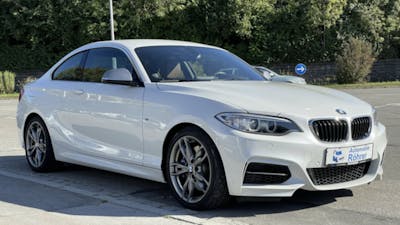 Ein weisser BMW M240i xDrive parkt am Strassenrand