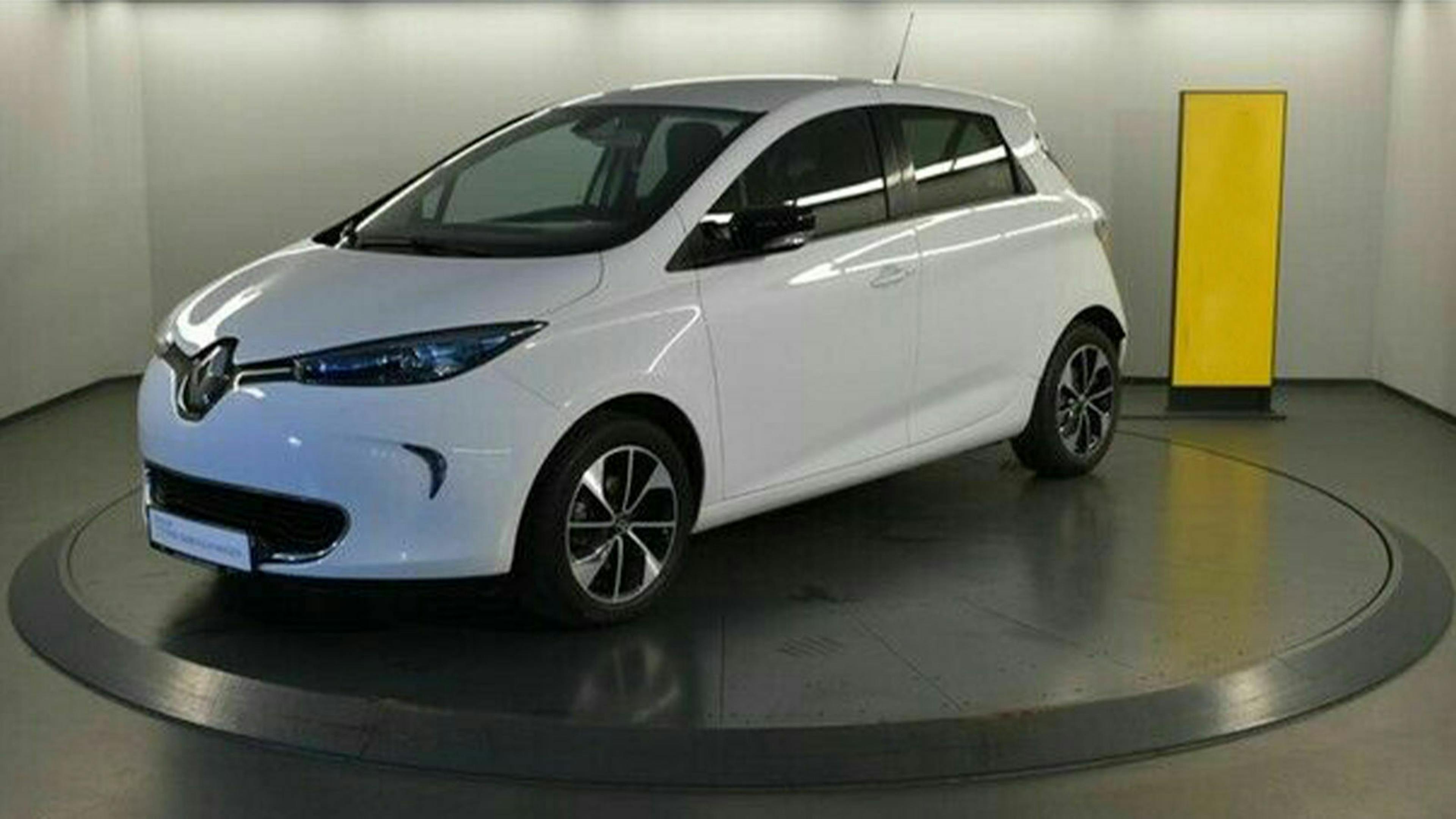 Ein weißer Renault Zoe steht auf einem grauen Untergrund vor einer weißen Wand.
