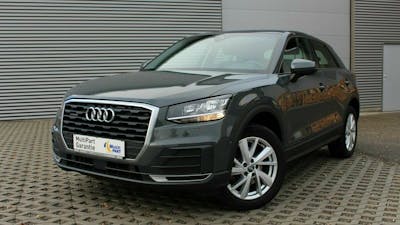 Ein dunkelgrauer Audi Q2 steht vor einem grauen Rolltor