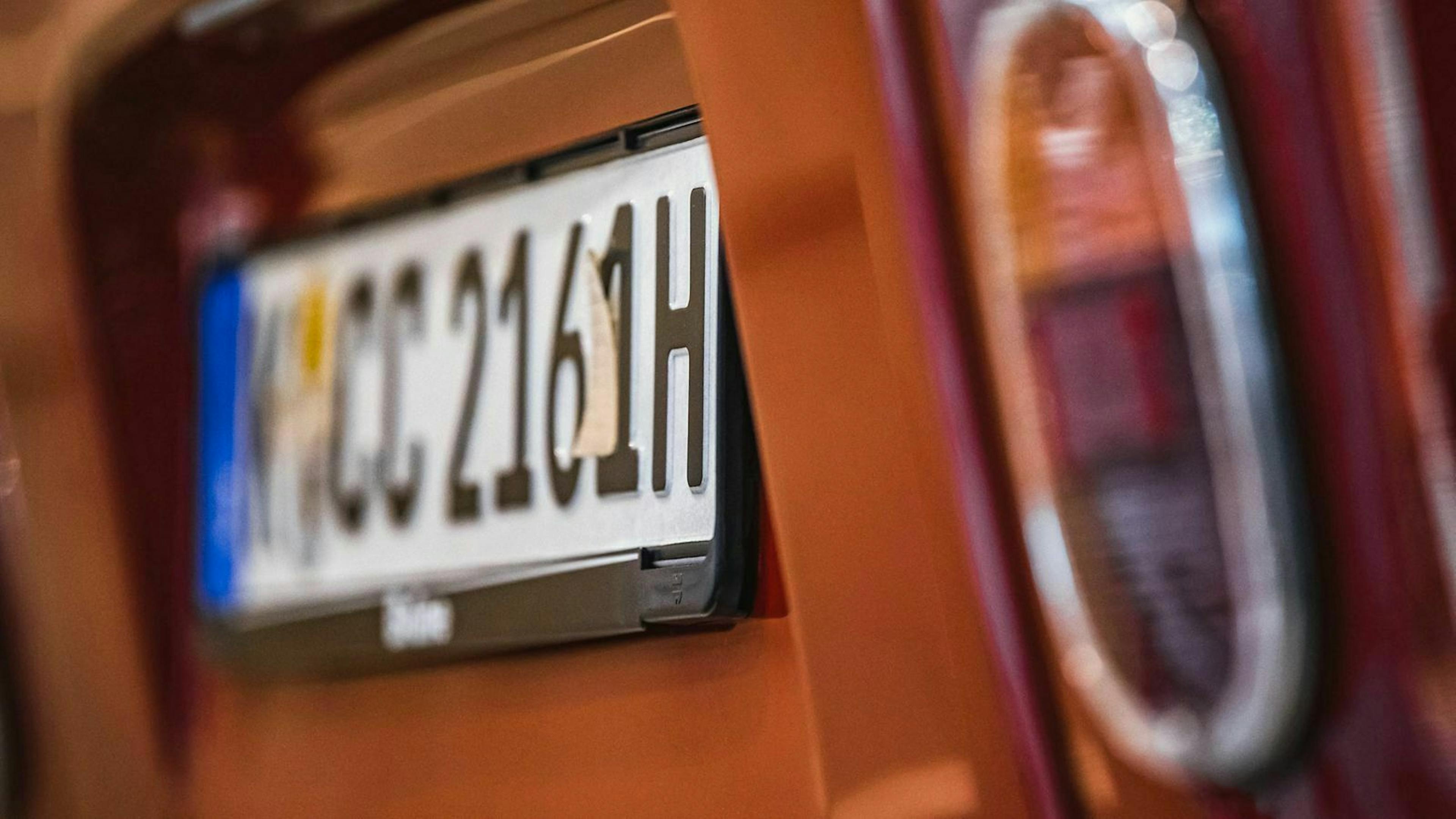 In Nahaufnahme ist ein H-Kennzeichen an einem orangenen Auto zu sehen.