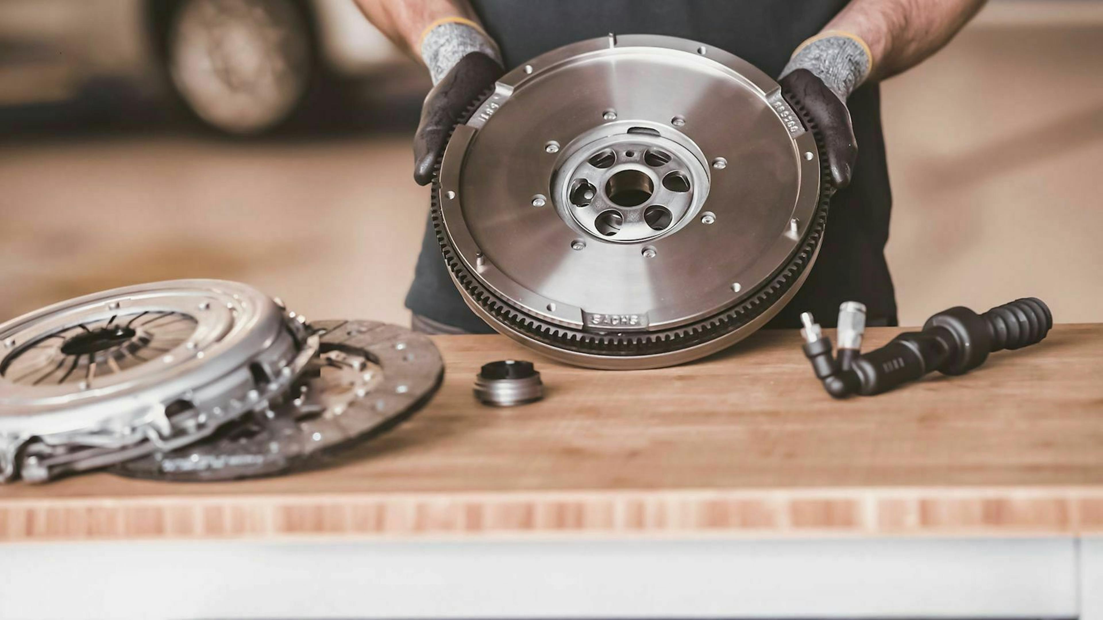 Ein Mechaniker bereitet die Komponenten für einen Kupplungswechsel vor und breitet die Teile vor sich aus. 