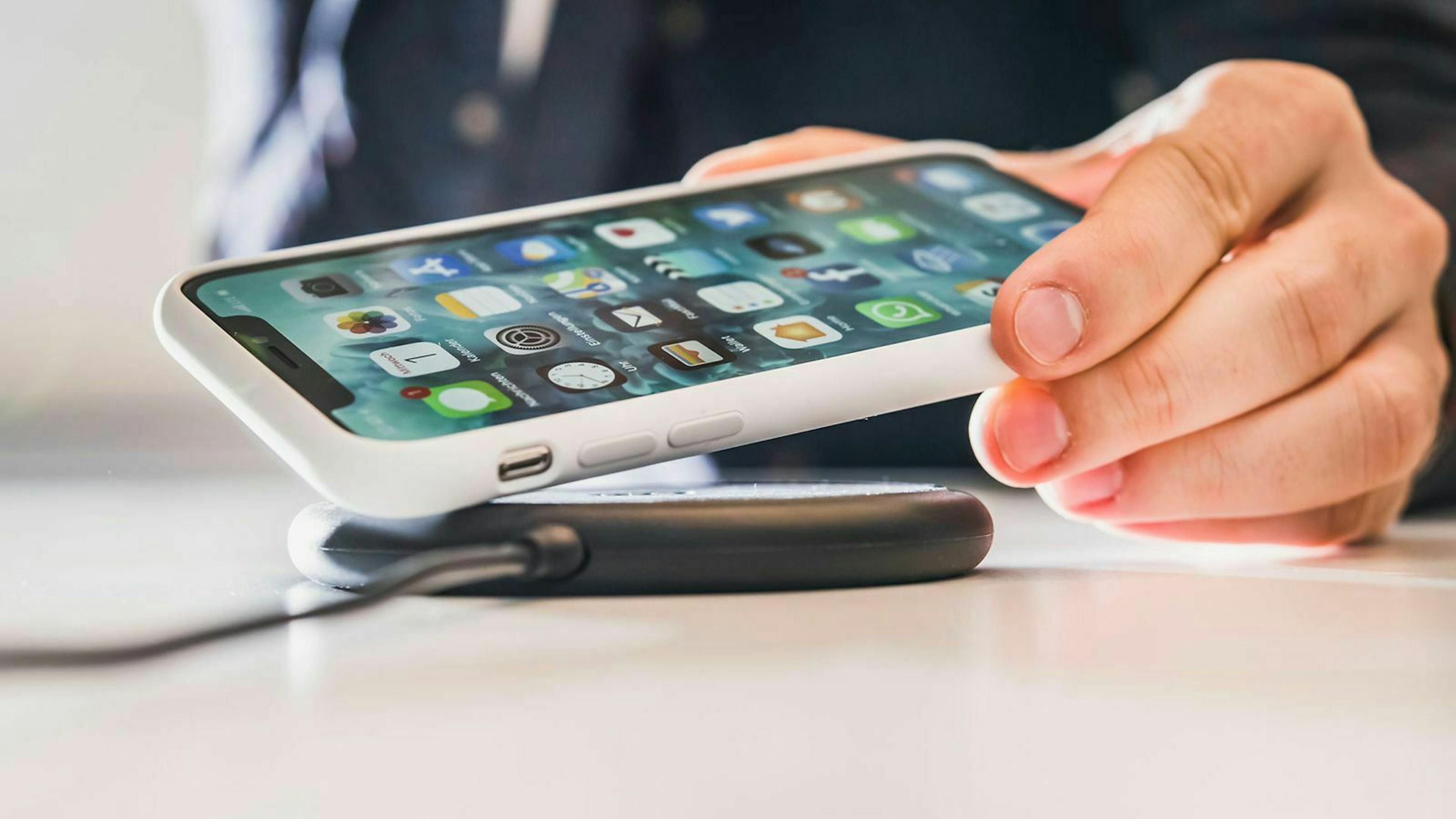 Jemand legt gerade sein Smartphone auf eine Ladeschale für kabelloses Laden. 